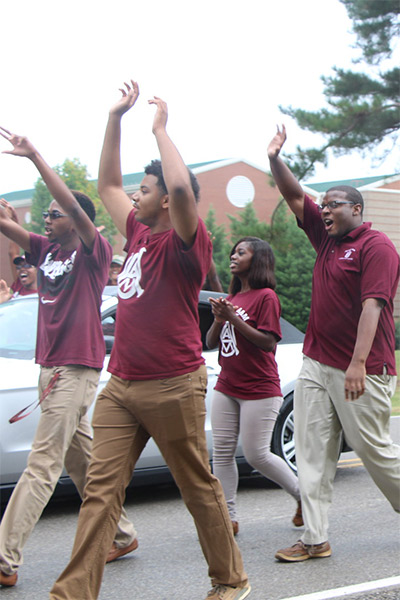 Members of a student organization march and wave in a Homecoming parade