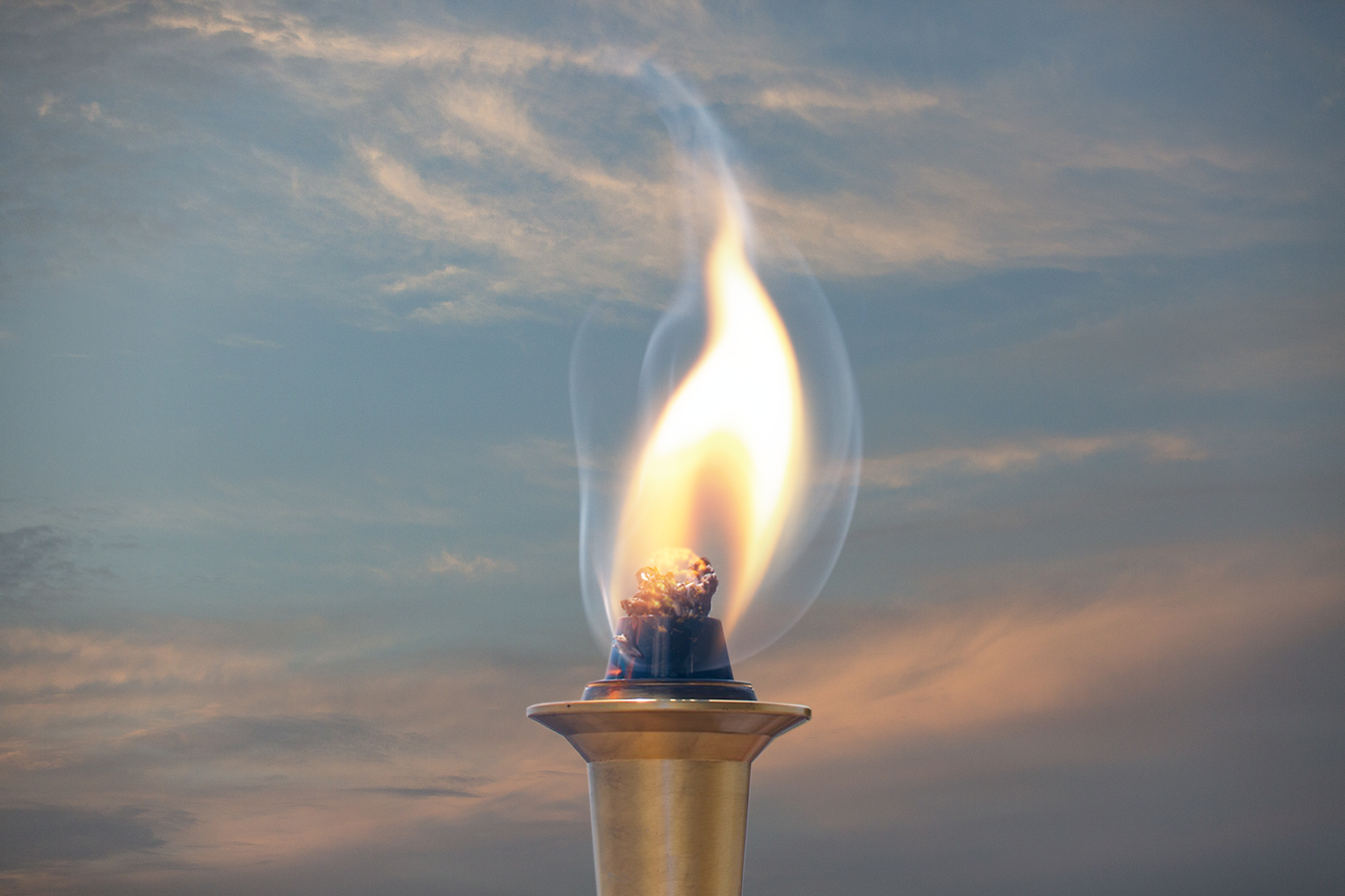 Photo of large torch with fire and sky in the background
