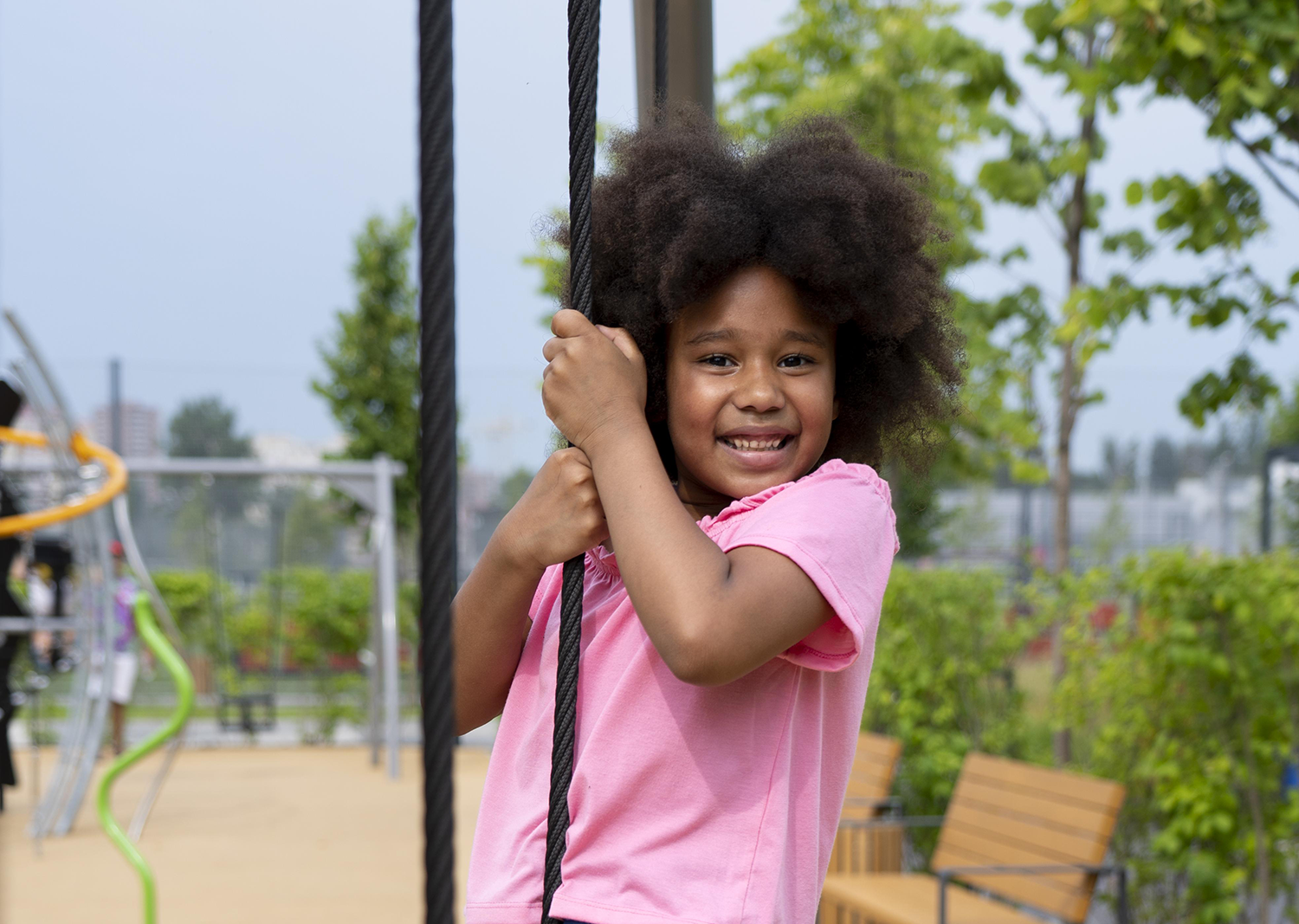 Little girl playing on a playground with two children on a slide behind her