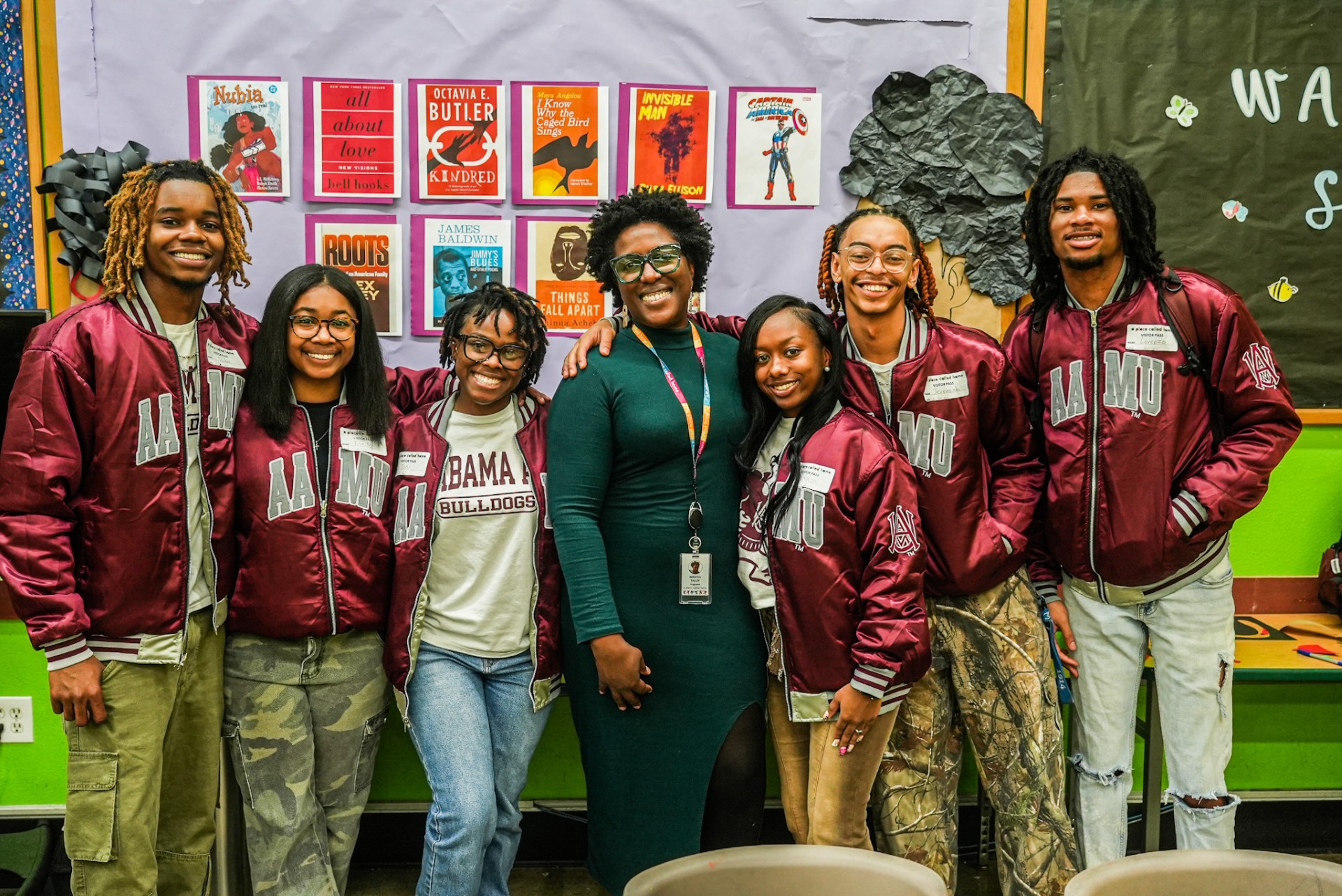 Members of Crew 75 and Bernyce Talley Smile at the camera in front of one of two bulletin boards they helped decorate
