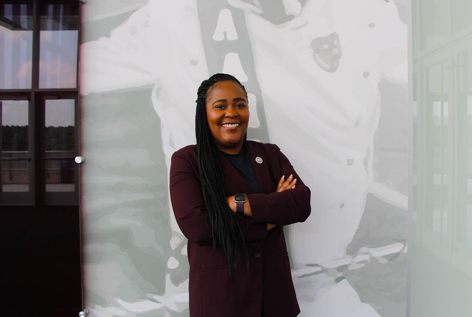 Erika Baldwin in maroon suit with arms crossed and smiling in a room in the AAMU Event Center