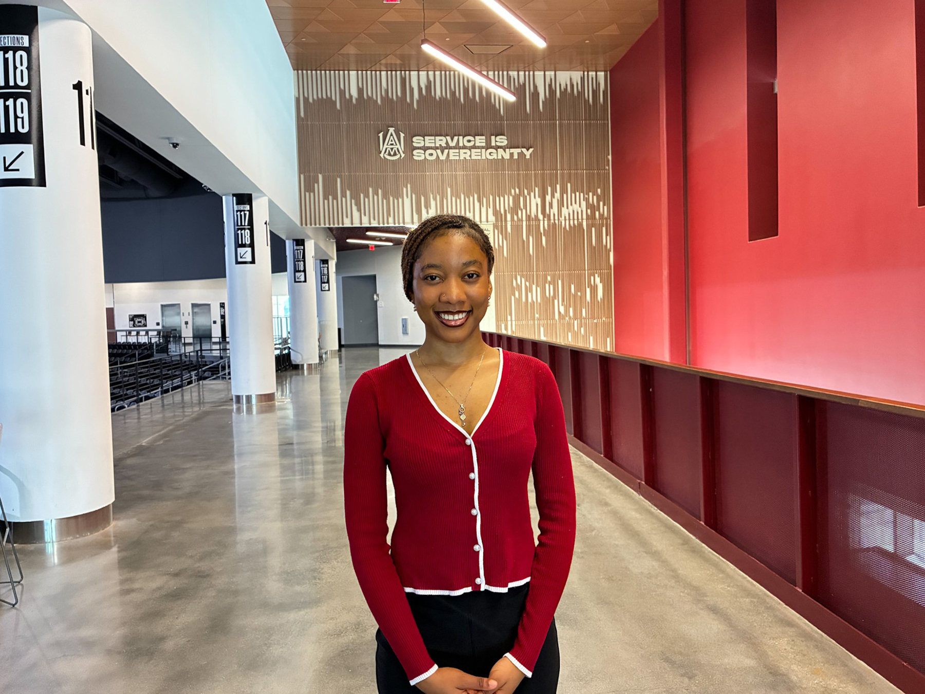 Jamie Pearl Chia smiles in front of the Service is Sovereignty sign on the second floor of the AAMU Event Center.