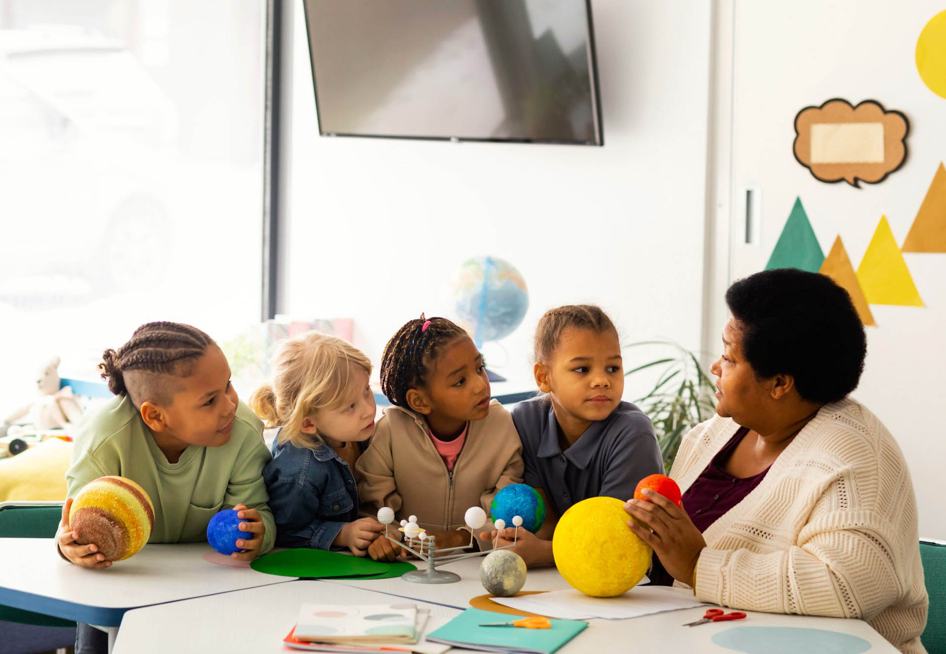 Teacher teaches four young students about planets