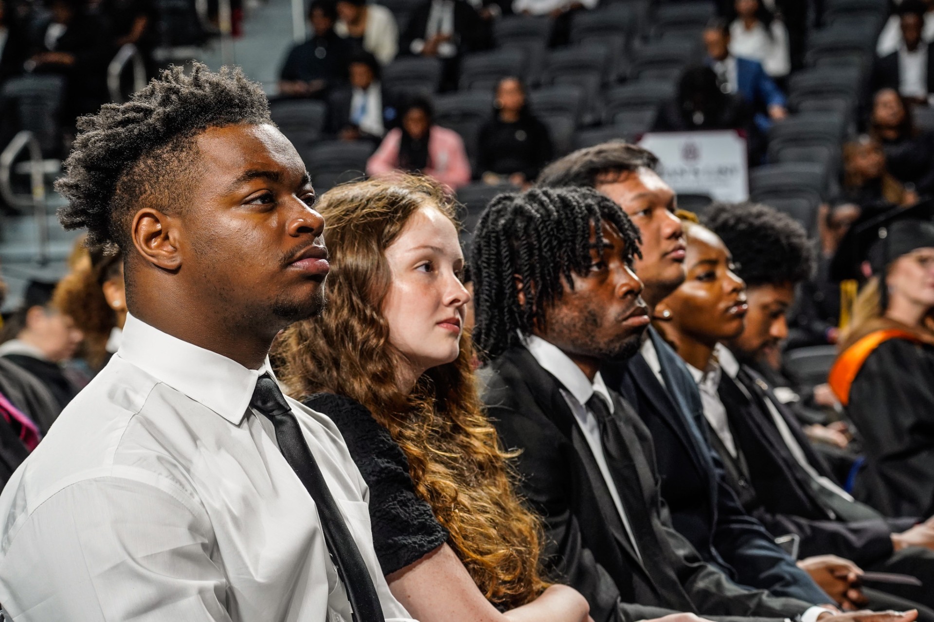 Five seated students look to the stage as they receive academic honors