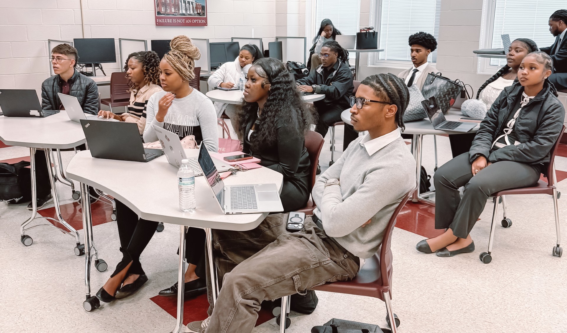 12 students selected for the AAMU Dollarcraft Program seated at four tables, listen to mentors from Blaze Group