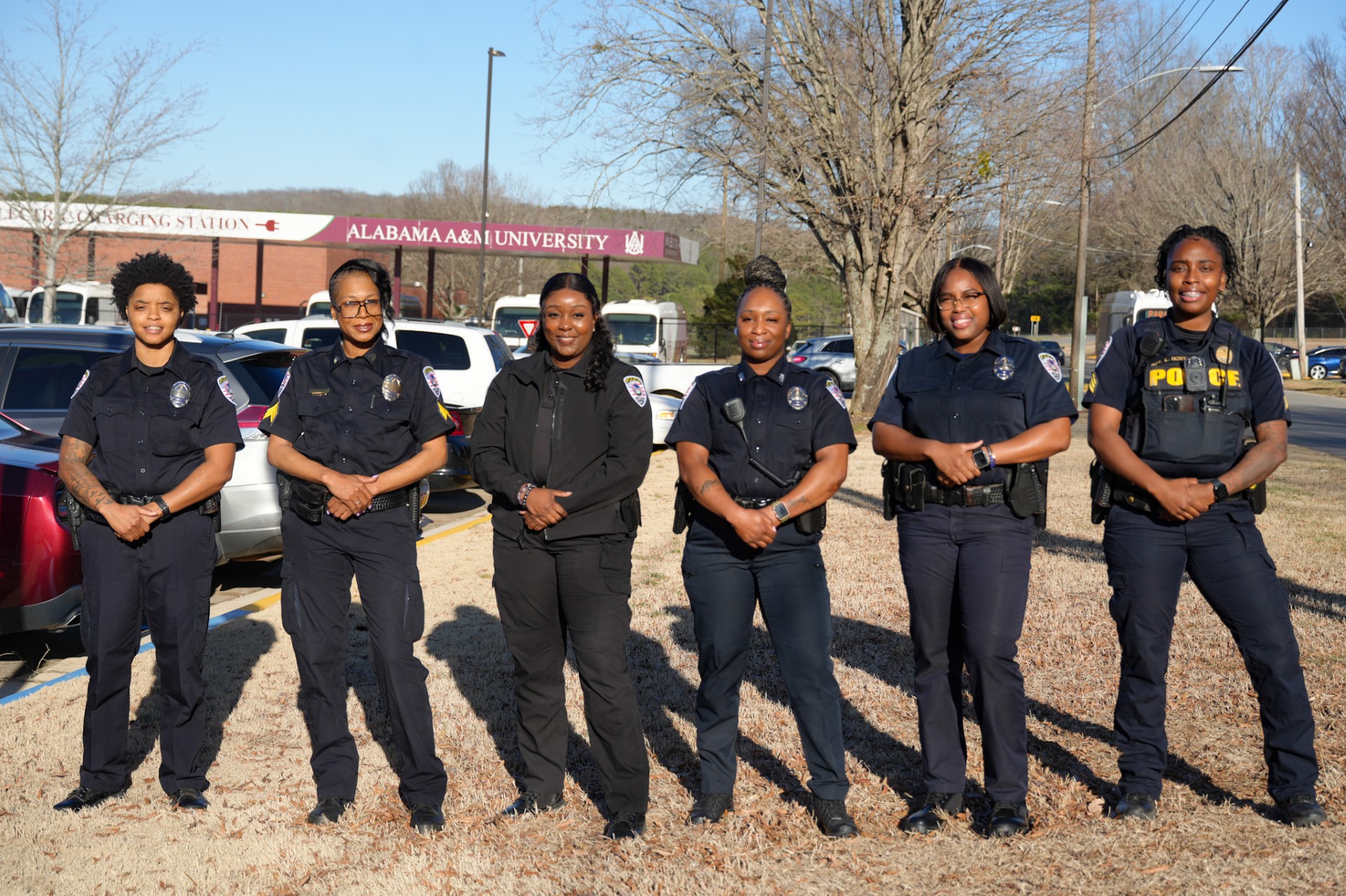 Officer Letrice Ragland, Sergeant GreshiaMonic Tice, Lead Investigator Destiney Toney, Officer Neyema Bey, Officer Alicia Bell, Sergeant Latraza Horton stand on grass in front of BTS Charging Station and sign that says "Alabama A&M Univesity"