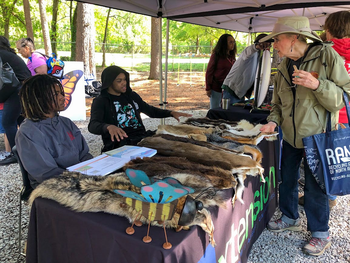 Outdoor Extension event with two students talking to woman