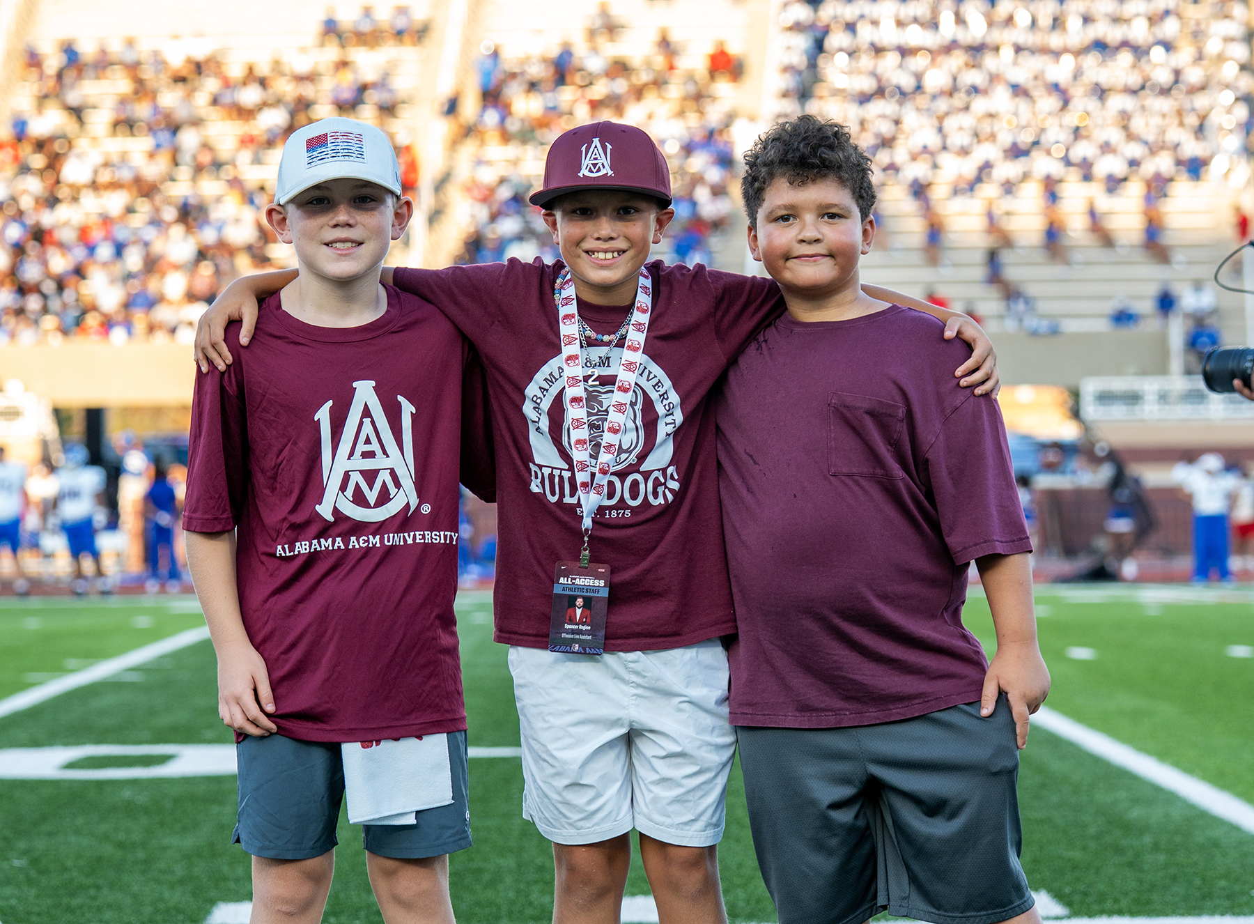 Three young students smiling on the sidelines at a recent AAMU football game at Louis Crews Stadium.