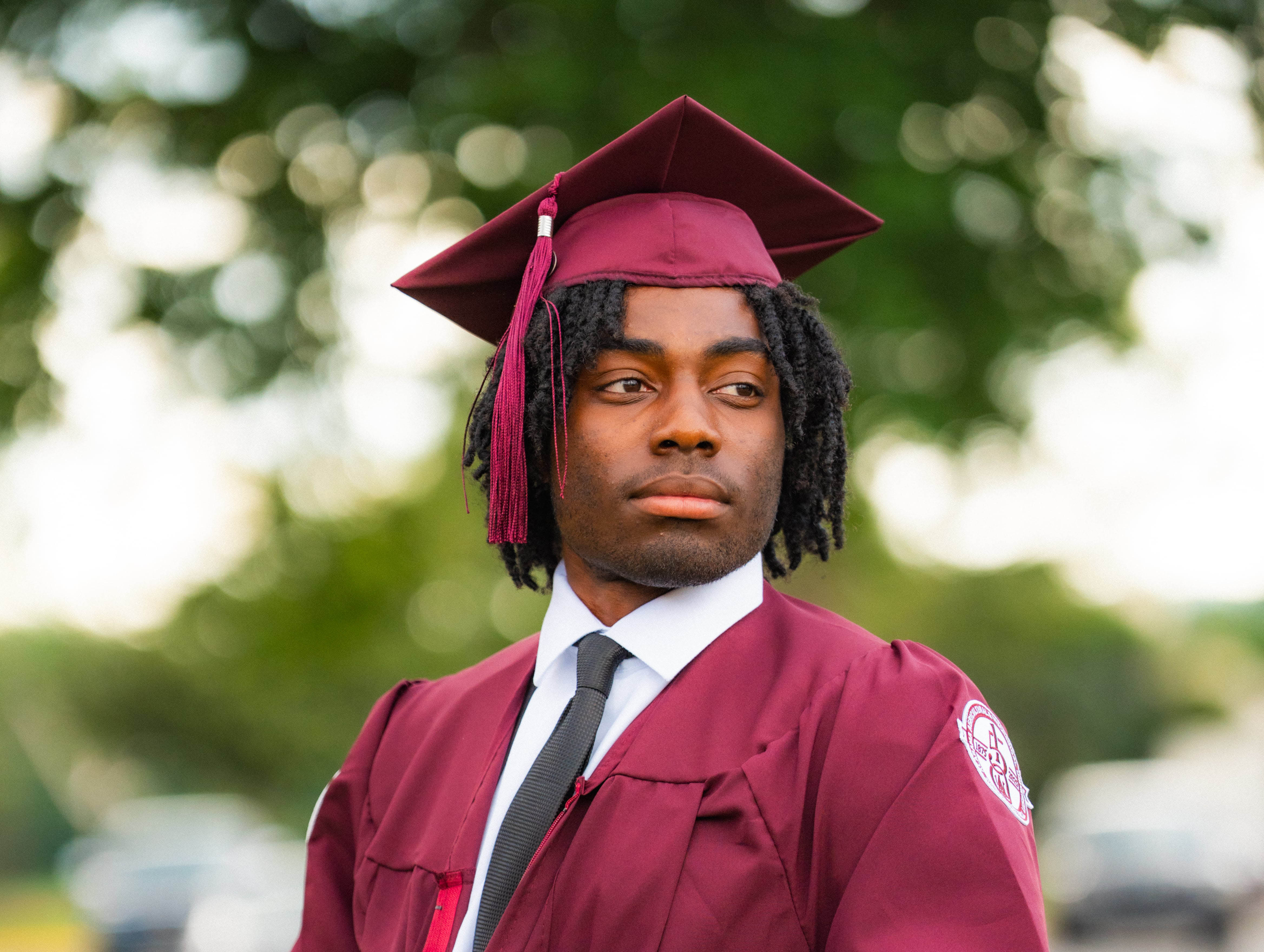 Freddie Lawrence wears AAMU cap and gown outside on the AAMU campus