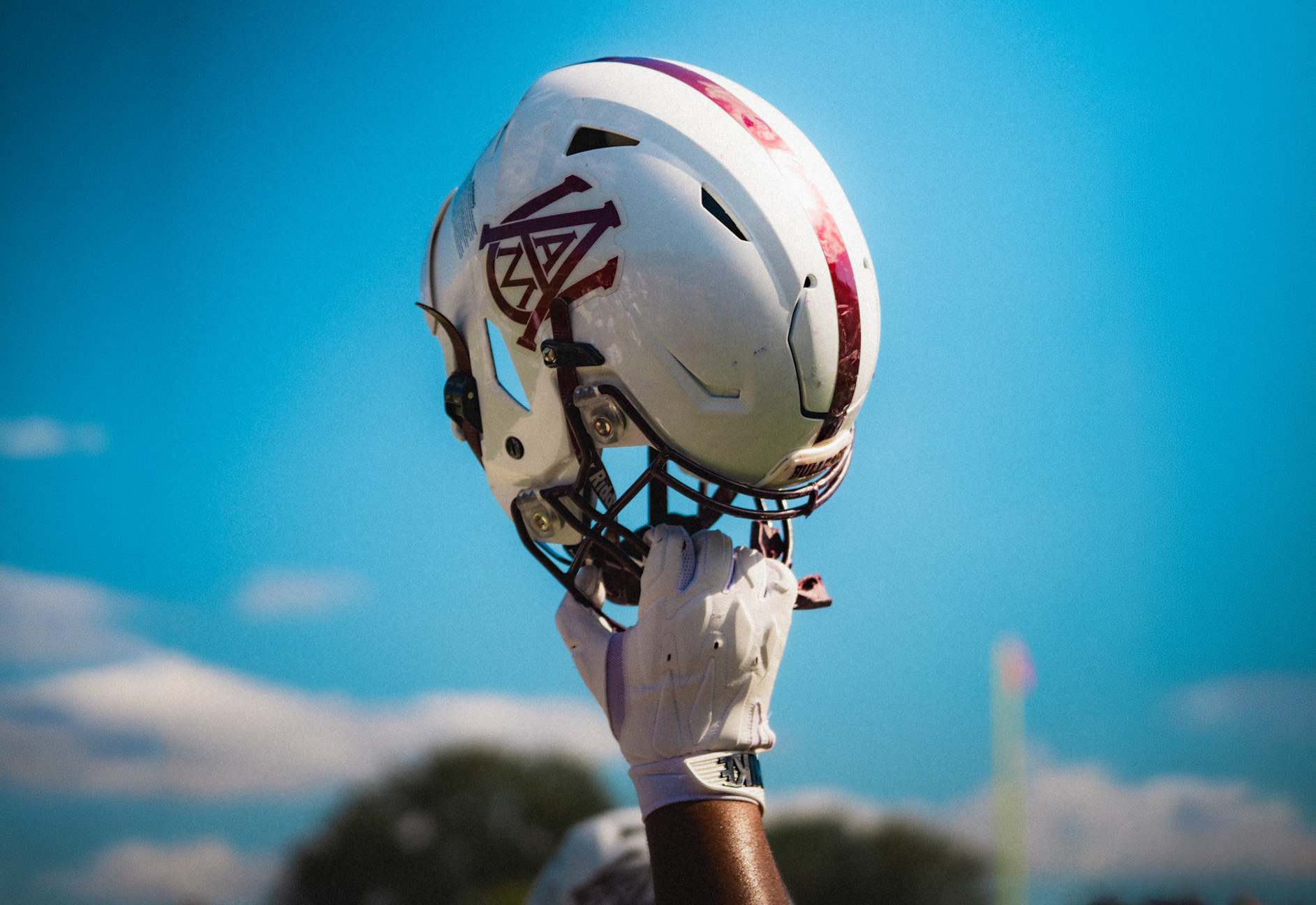 Football player holds his AAMU football helmet up in the air.