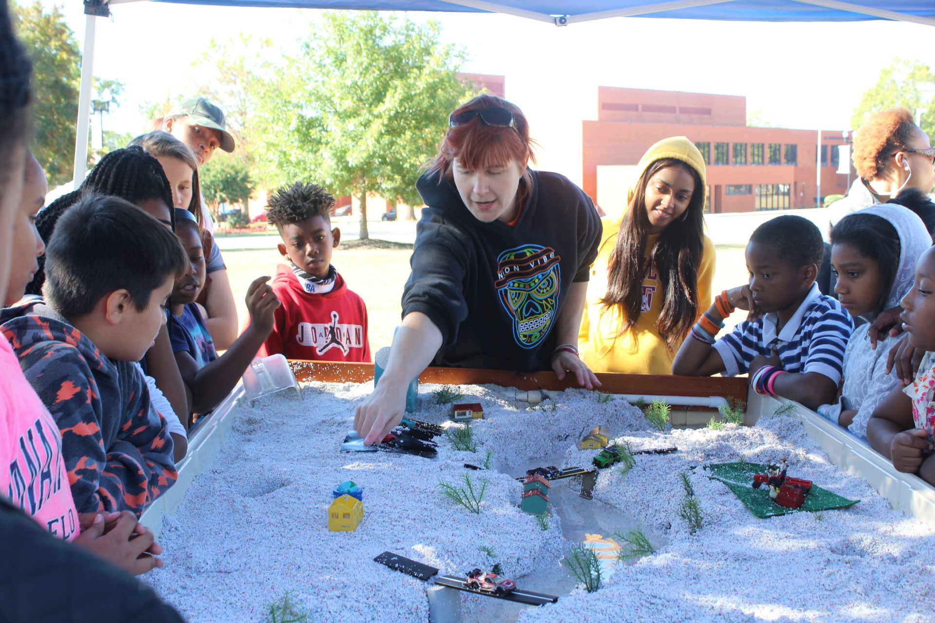 U.S. Forest Service member points to a demonstration surrounded by young students