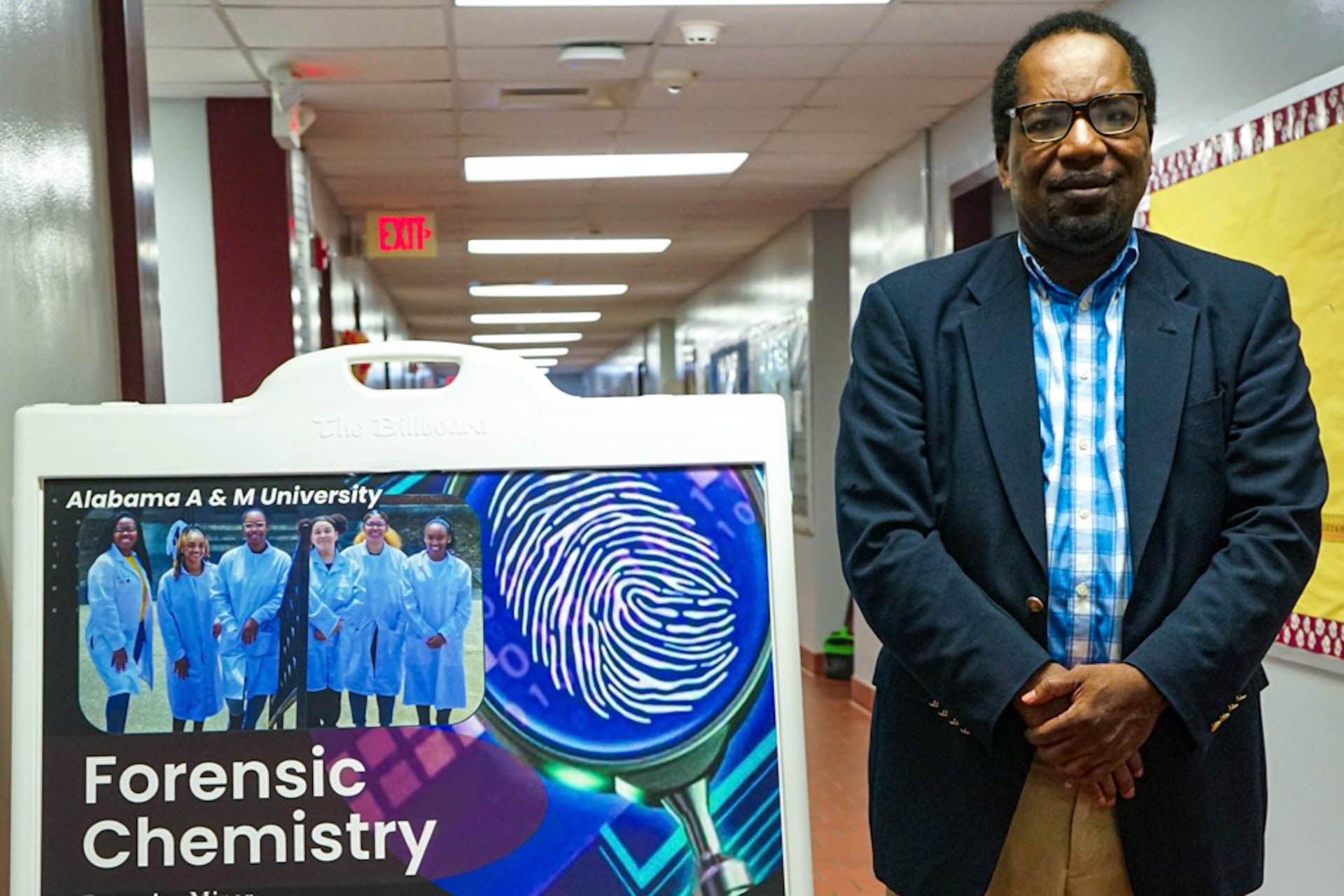 Dr. Jules Guei stands next to forensic chemistry sign near his office