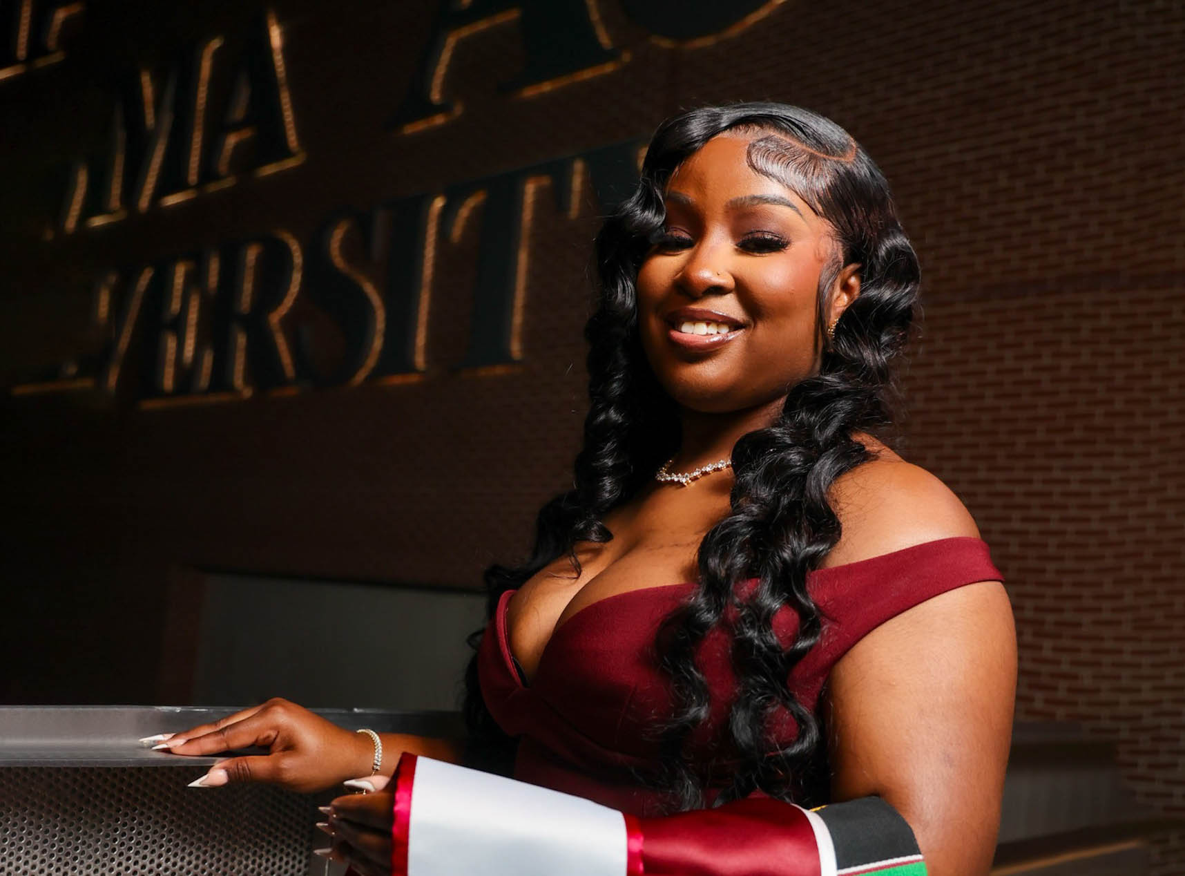 Hadassah Meralus holds graduation stole in front of AAMU Event Center