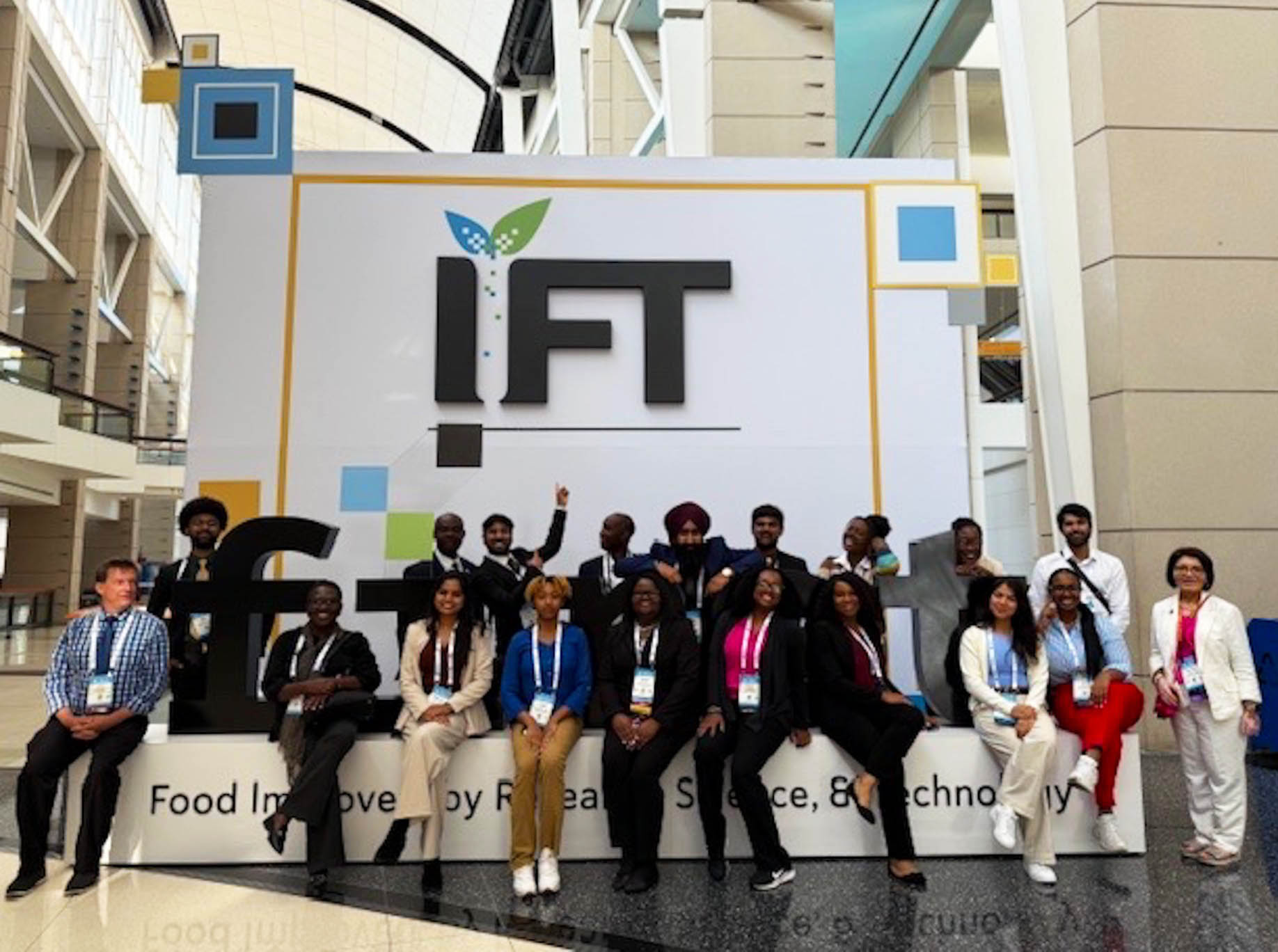 19 AAMU food science graduate students, faculty and staff pose in front of large IFT signage at IFT First Conference in Chicago