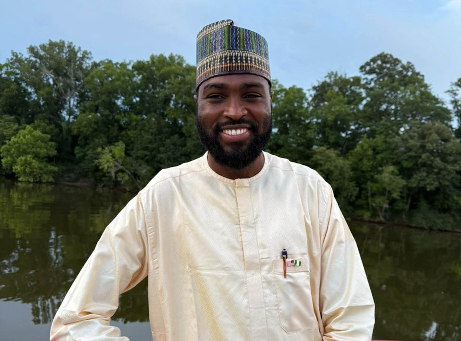 Abdullahi Jafar stands on a boat with water behind him in his home country of Nigeira