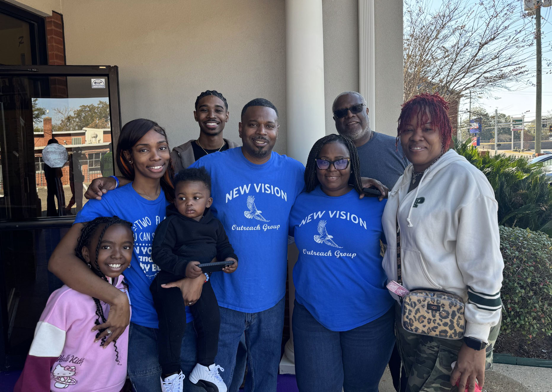 Jay Mayes stands behind his family at Annual Thanksgiving Giveaway in Montgomery, Alabama