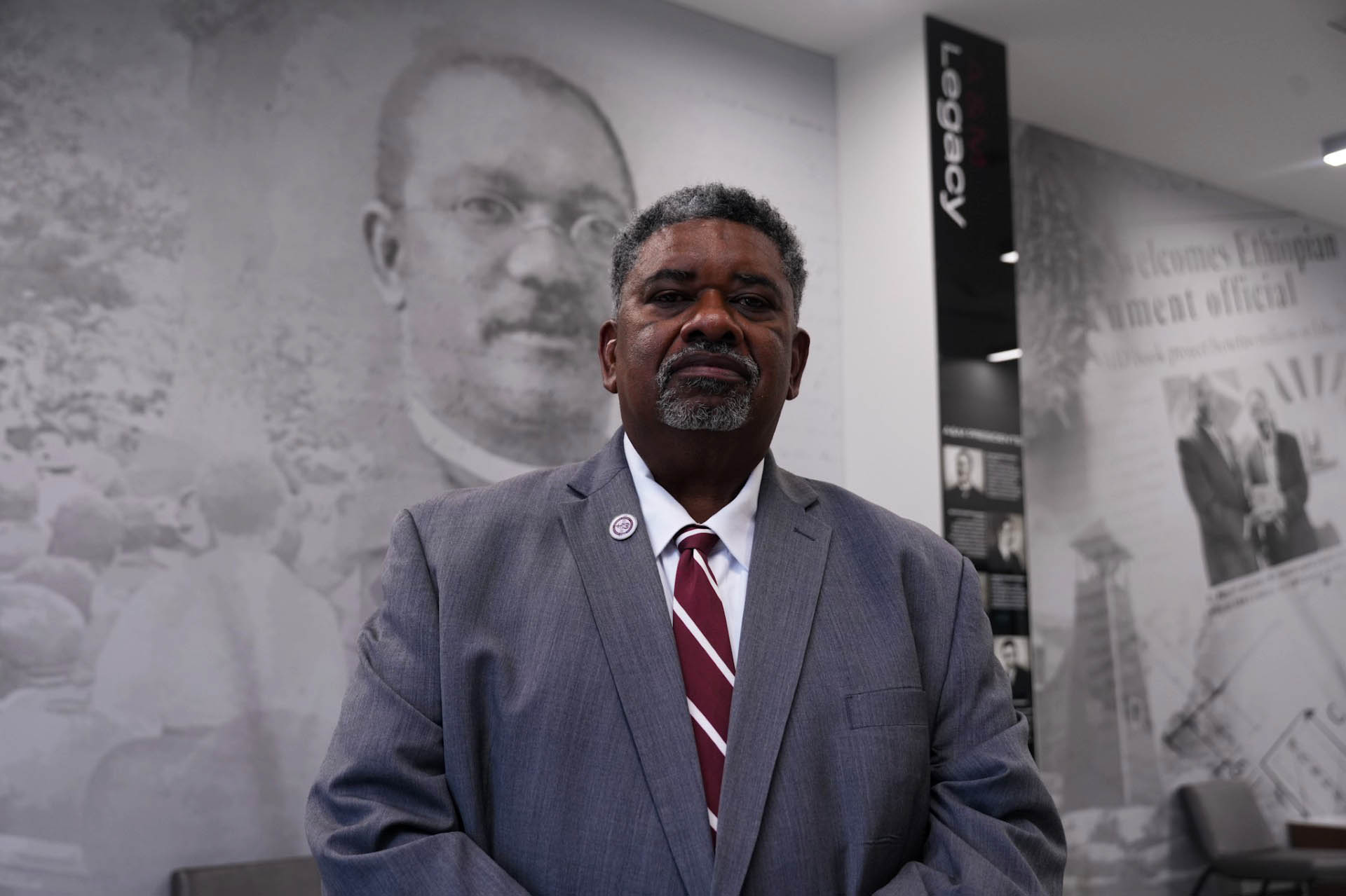 Elvin Jenkins stands in front of an image of AAMU Founder William Hooper Councill on a wall in the Event Centerr
