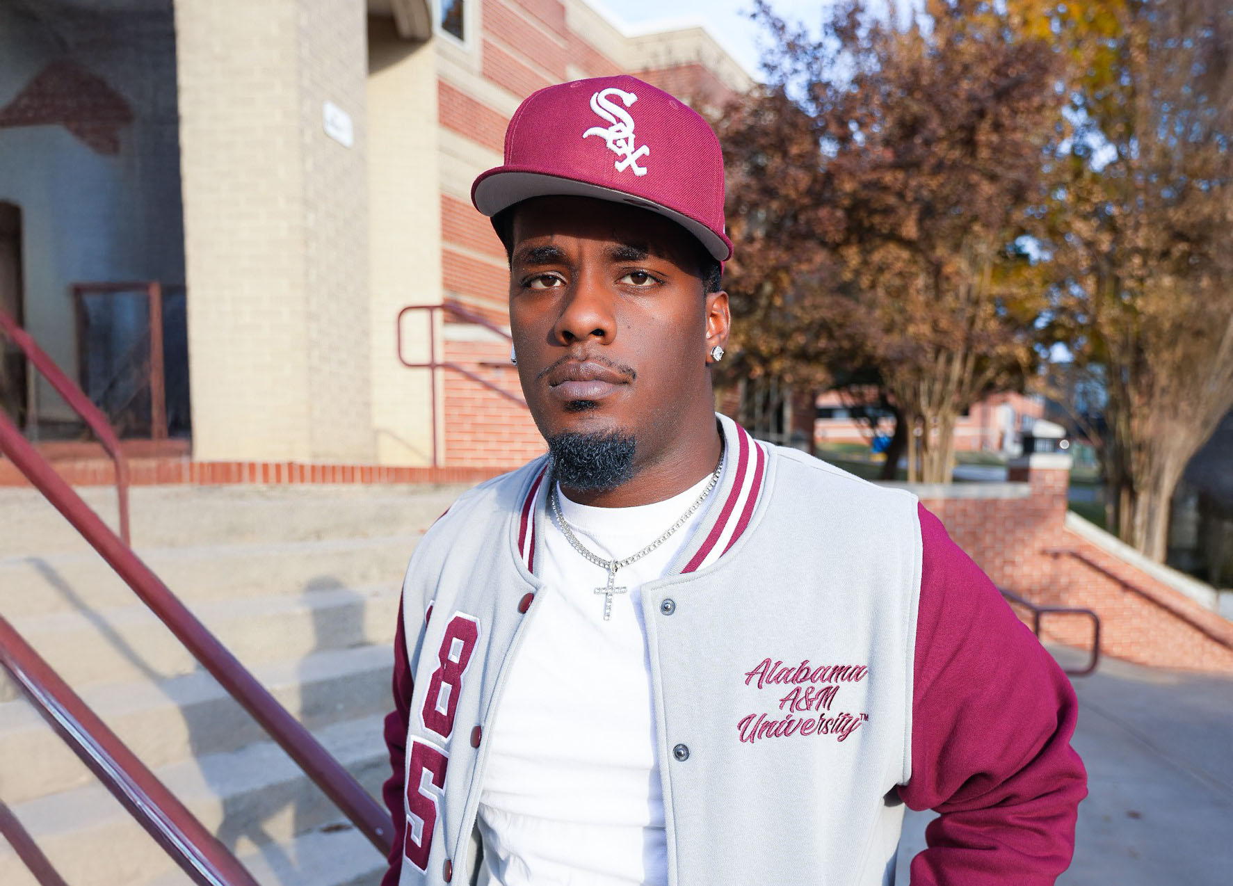 Jeremiah Johnson wears an AAMU jacket and White Sox baseball hat outside of the AAMU library
