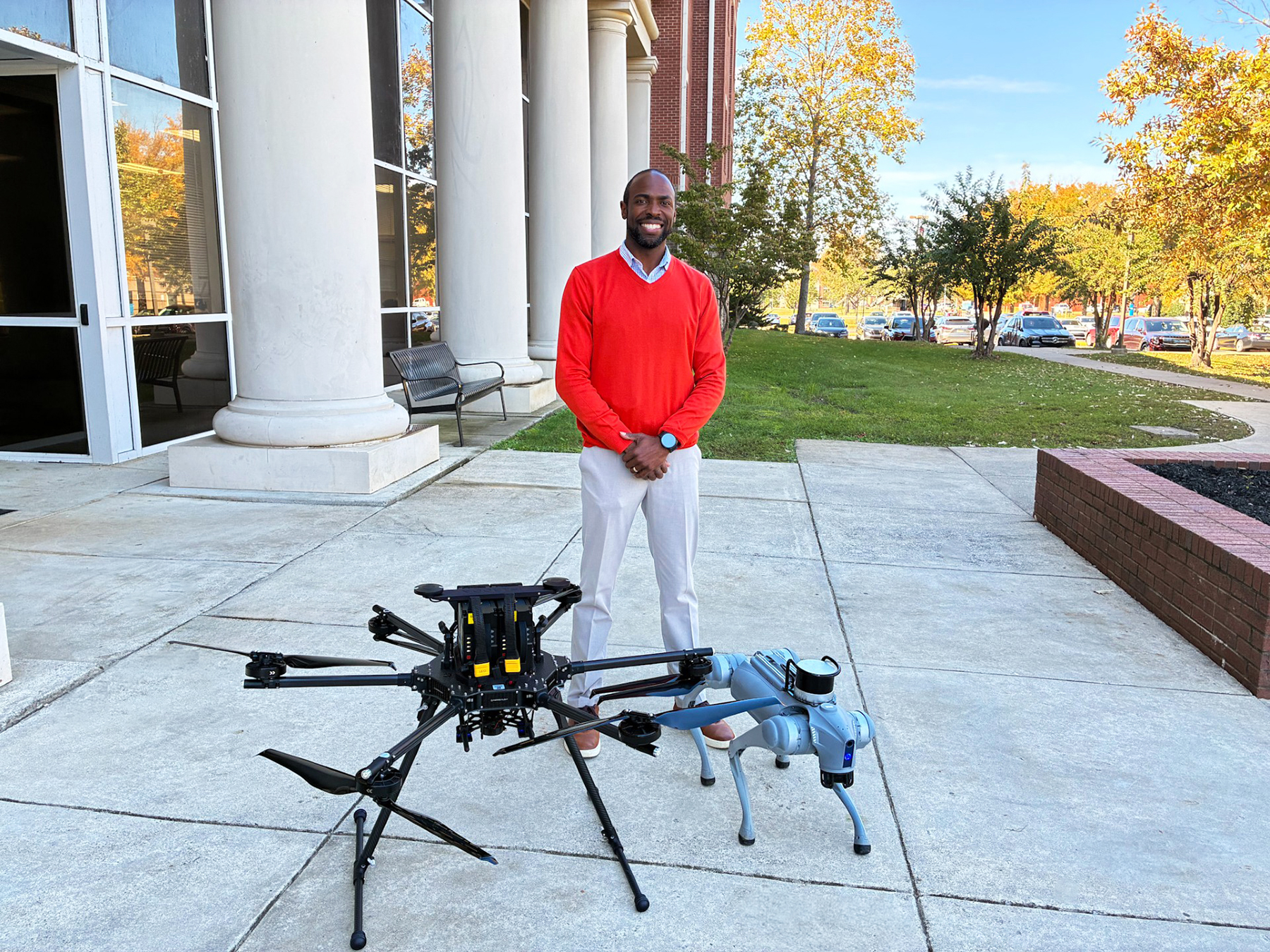 Justin Vaughner, Alabama A&M University alumnus and Unified Drone Unit lead, stands with a research drone and E-Butch, one of the university's two robotic dogs.