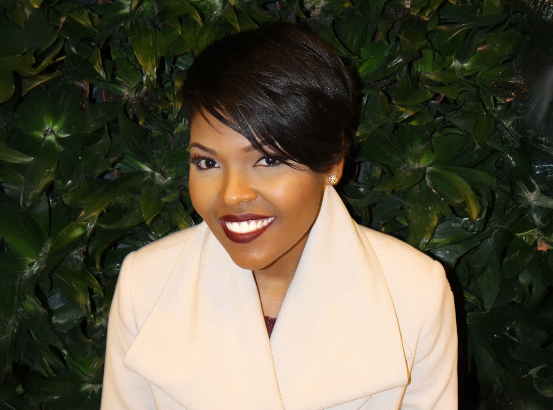 Professional headshot of Dr. Kimberly S. Love with dark green foliage behind her
