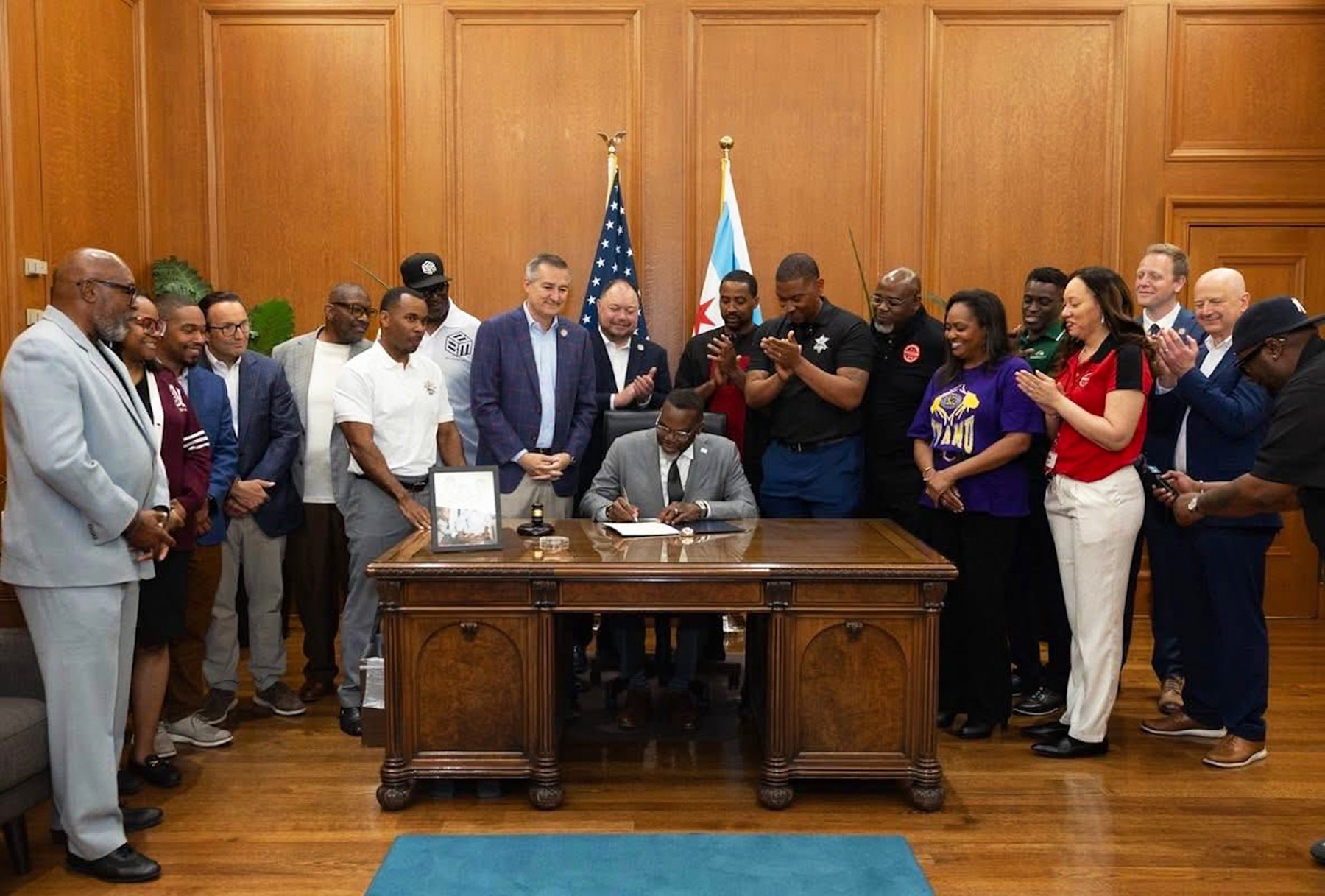 Mayor Johnson signs proclamation while AAMU and Prairie View alumni and representatives from Black Baseball Media and the Chicago Cubs clap while looking on