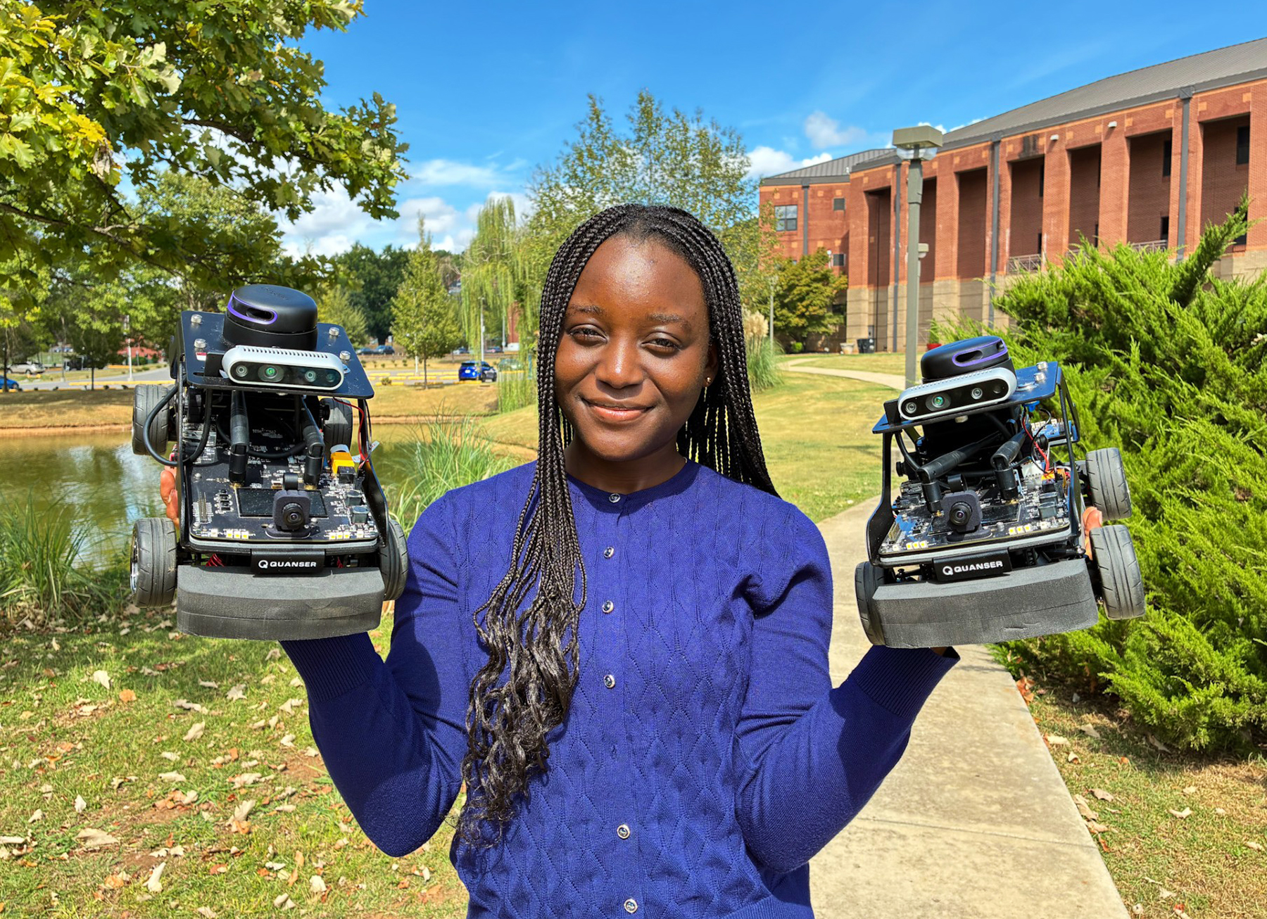 and avoid repeating too much information from the article. Alabama A&M University computer science senior Mercy Akinyemi holds two autonomous research vehicles outside the Bond Engineering Building. Her research in autonomous vehicles and robotics helped prepare her for a software engineering career at Meta.