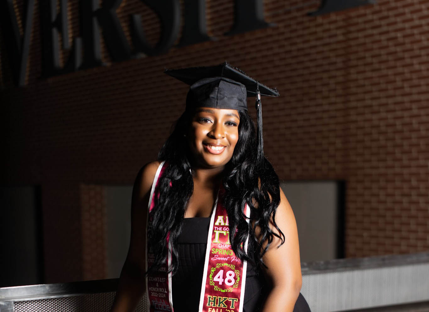 Nia Thompson wears graduation cap and stole outside the AAMU Event Center