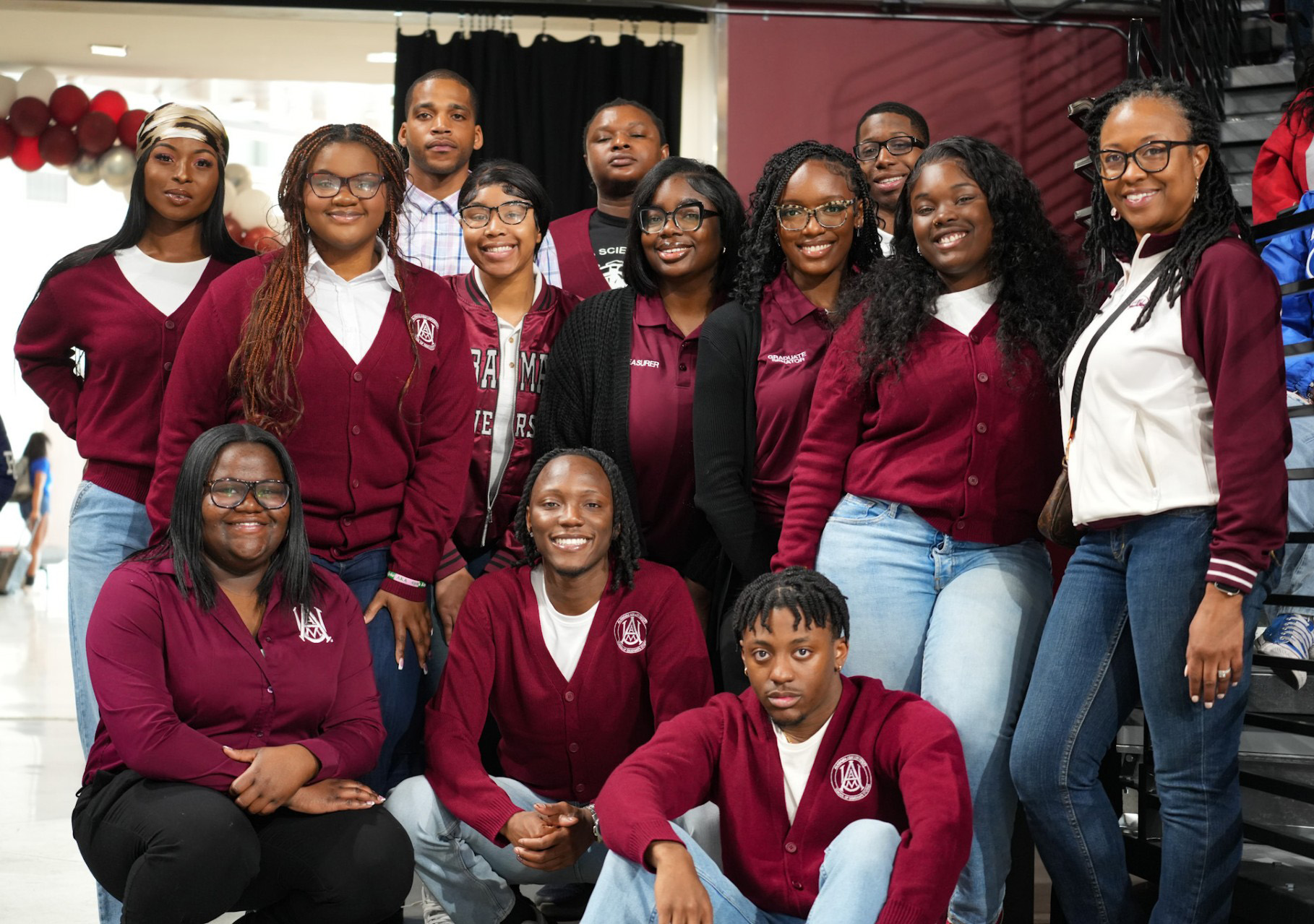 Group of 13 smiling students wearing Maroon & White sweaters