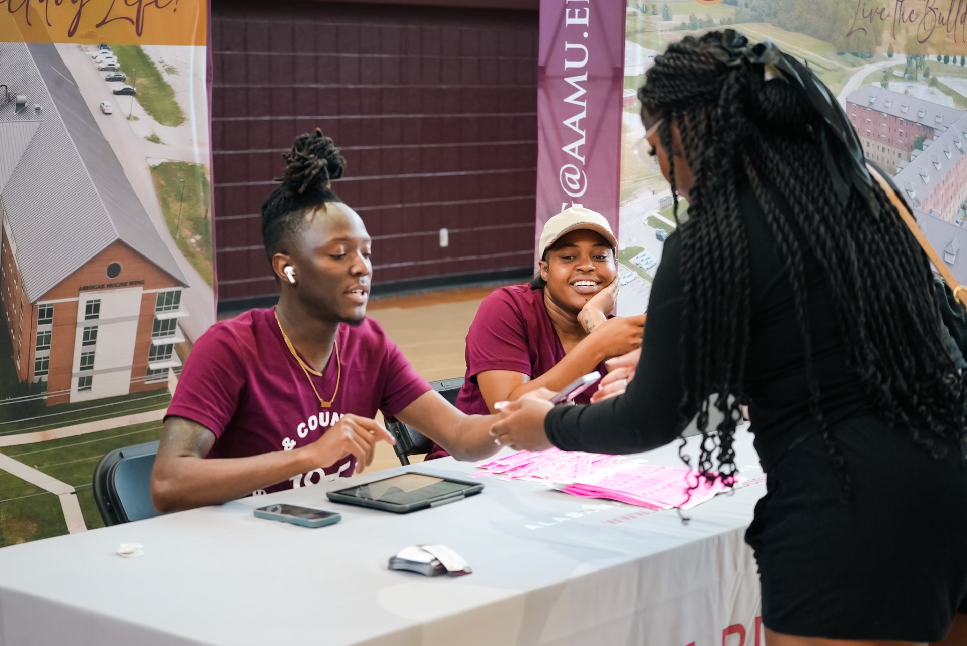 Two student seated at a desk helping a fellow student
