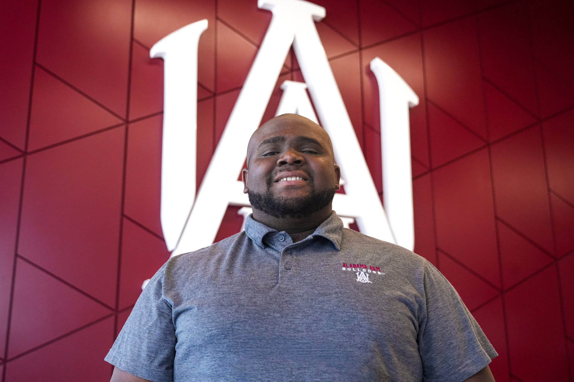 Jacob Ryan Pearson stands in front of the AAMU interlock logo in the Event Center