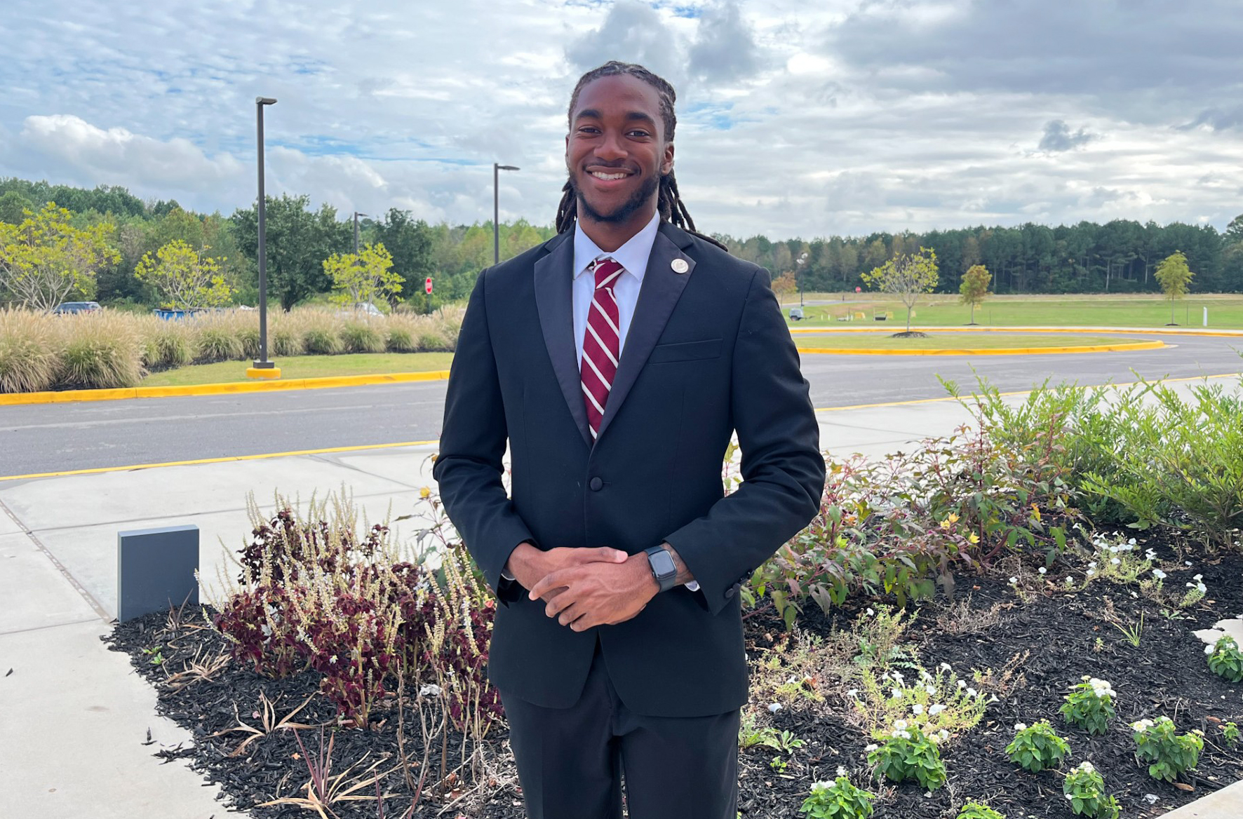 Timothy Smith III stands outside the AAMU Event Center with trees behind him