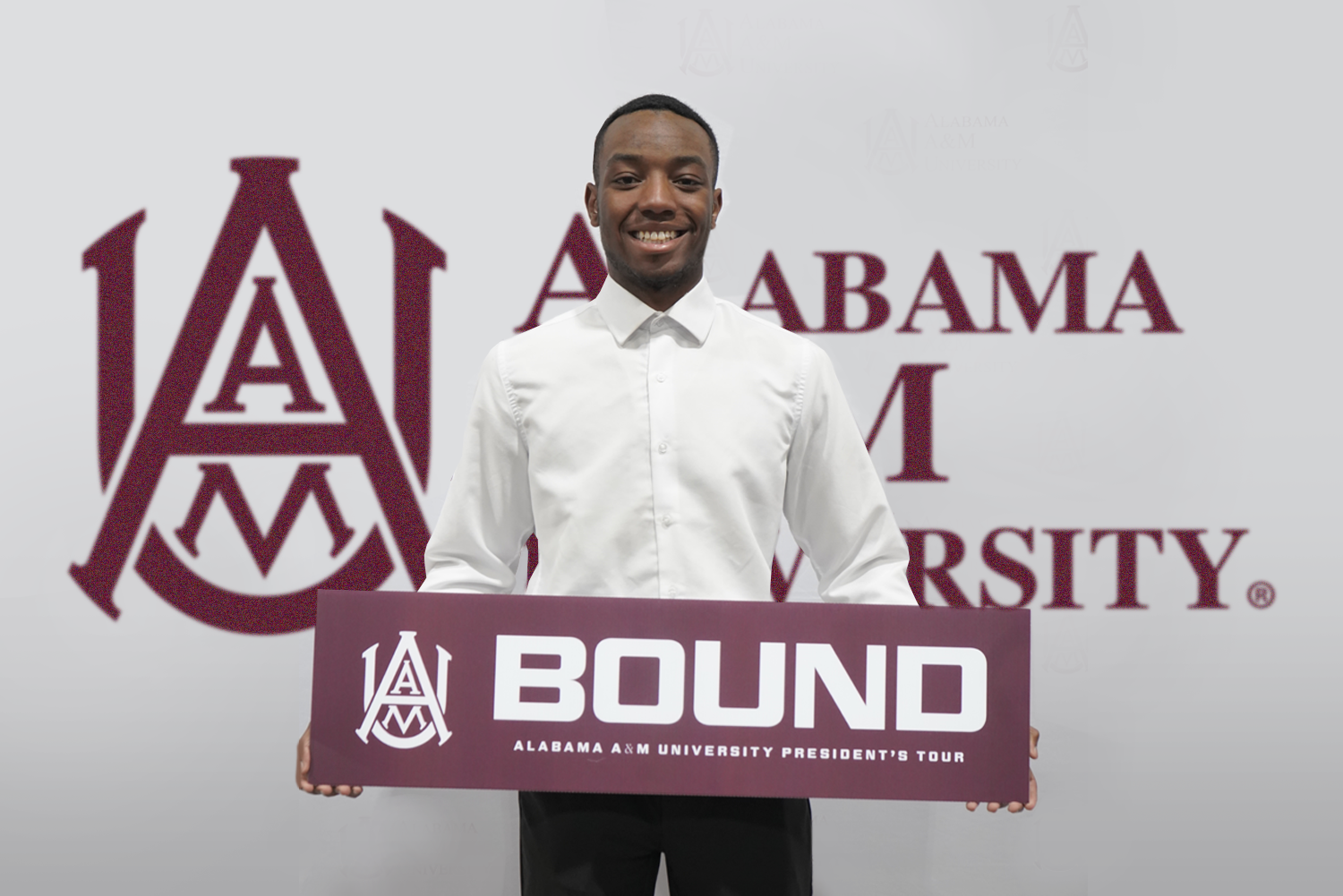Smiling male student holds sign that says "AAMU Bound"