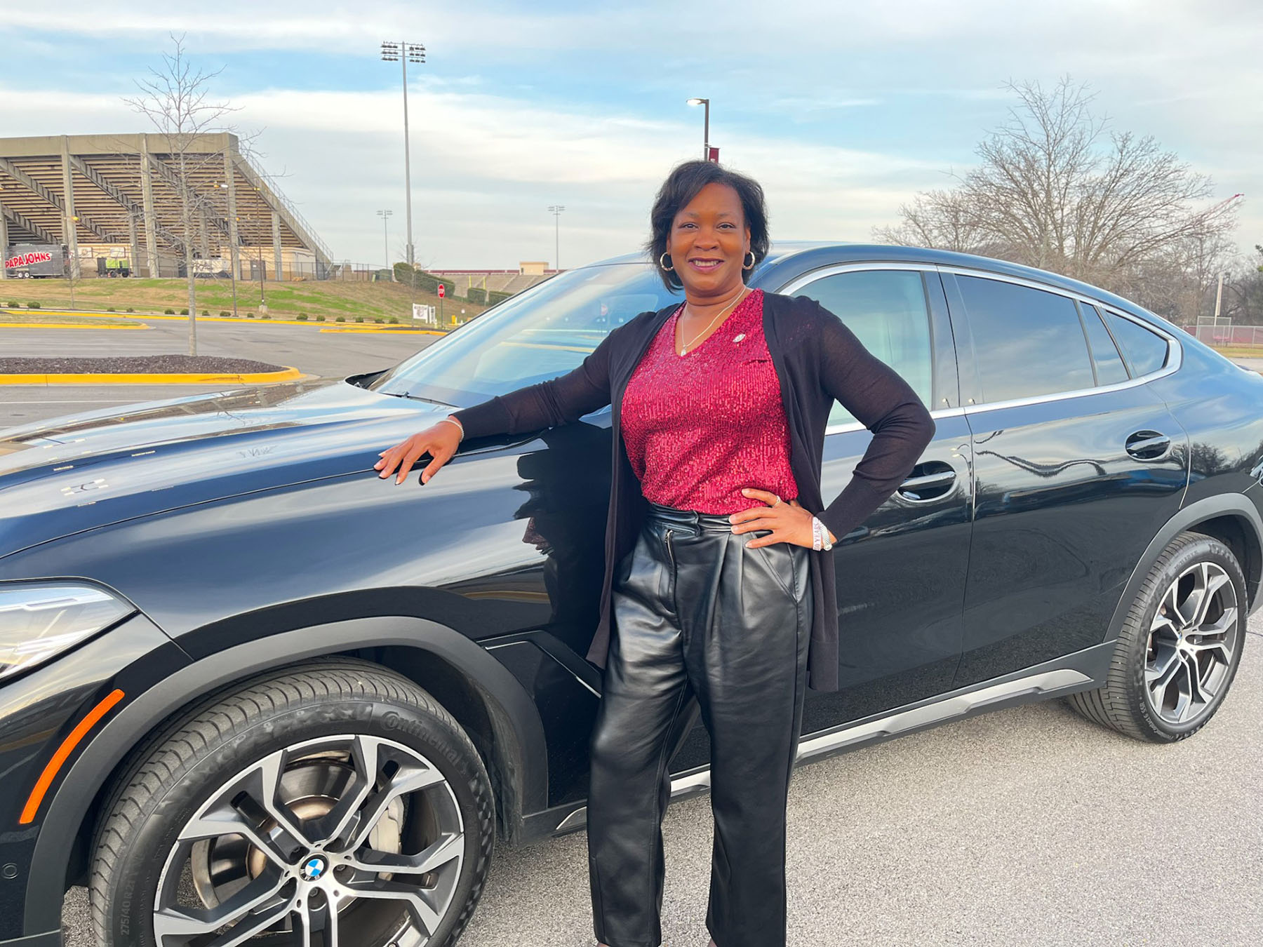Terra Foster stands next to current car in AAMU Event Center parking lot