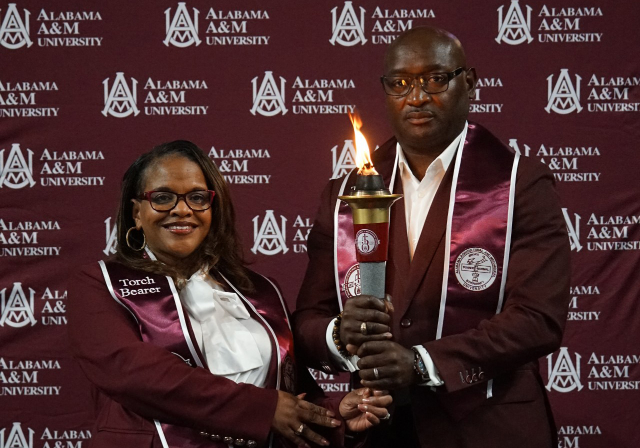 Two torchbearers Hold Torch on Stage at AAMU Event Center