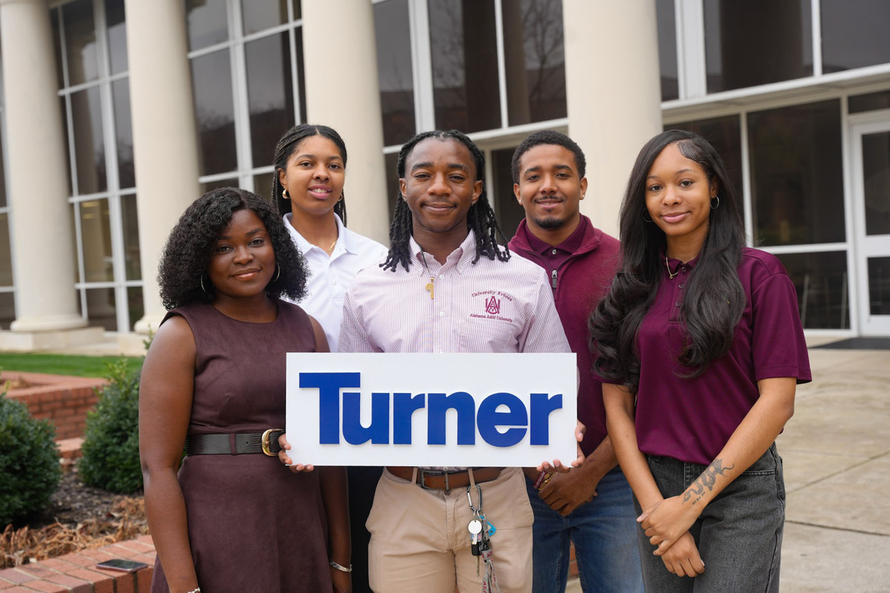 Kiswendsida Christelle Sanwidi, Camryn Cooper, Raymond Wilson Jayden Head, Ashanti Sterling stand outside the Bond Engineering Building with Wilson holding "Turner" sign