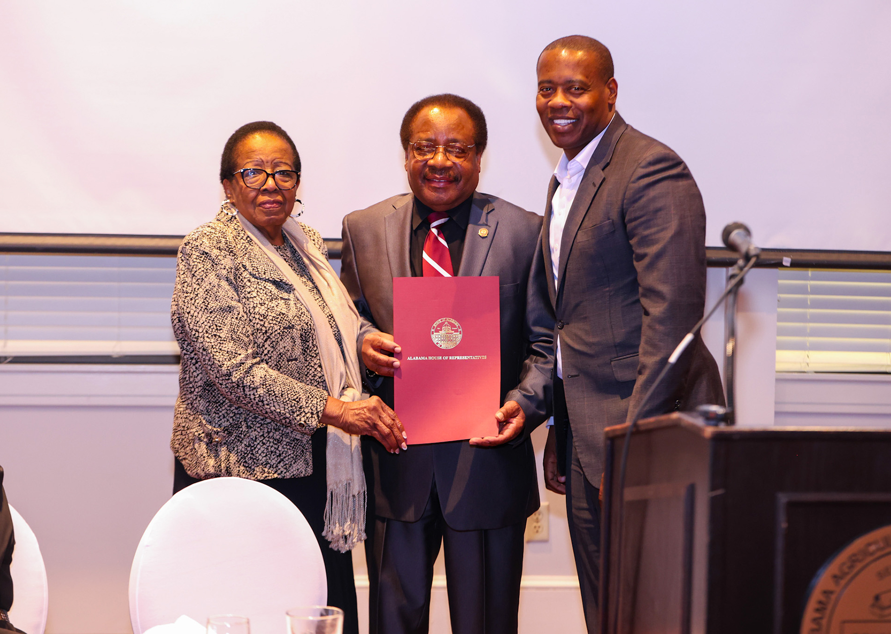 Alabama State Reps. Laura Hall and Anthony Daniels stand beside Dr. Lloyd T. Walker as they all hold a proclamation they presented Walker