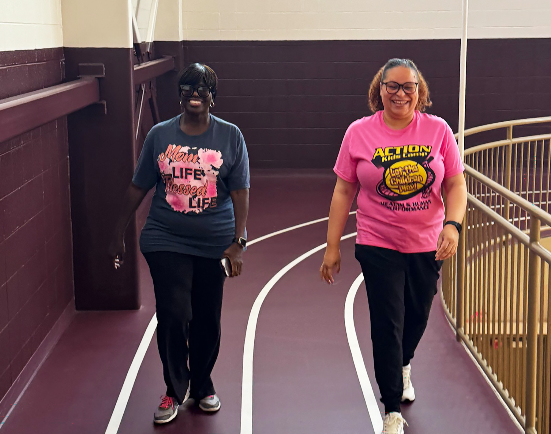Two AAMU employees smile while walking around indoor track at the University Fitness & Recreation Center on campus