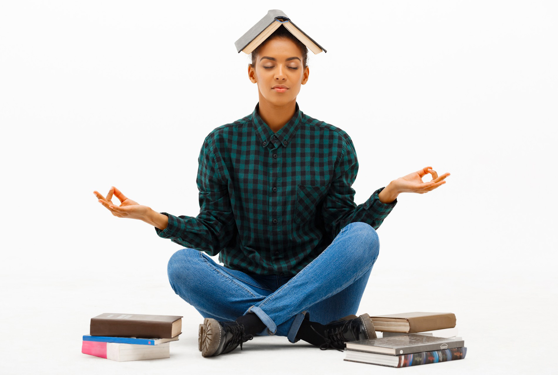 Female student seated on floor surrounded by books in the meditative lotus pose