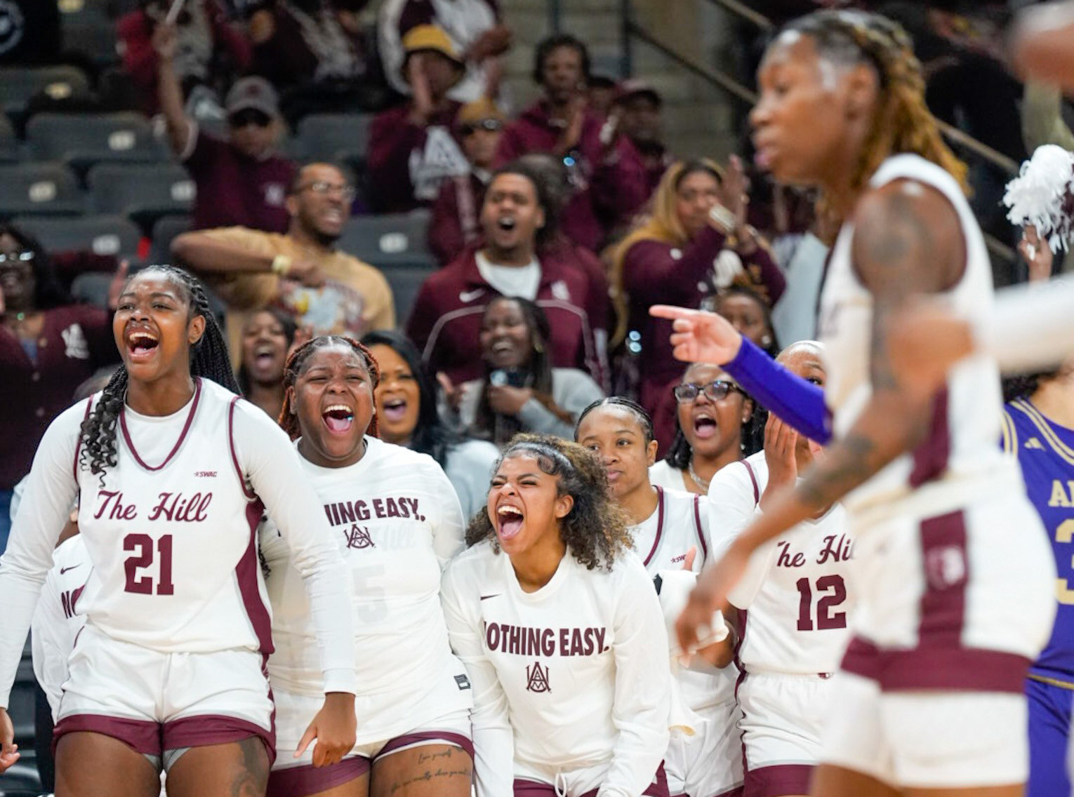 Seven members of the AAMU Women's Basketball Team cheer from the sideline as another menber of the team plays on the court during a recent home game at the Event Center