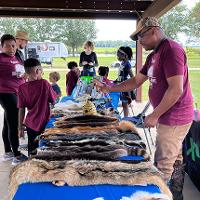 An agent stands with the skulls and skins display teaching participants about local wildlife.