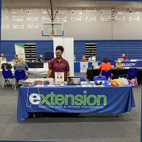 An agent with their information booth at a local school gym.