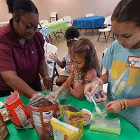 An agent works with three youth making a healthy snack.