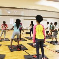 A local school class is in the school gym playing on the Extension dance pads for exercise.