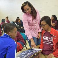 High school students work with an Extension agent, going over a science chart.