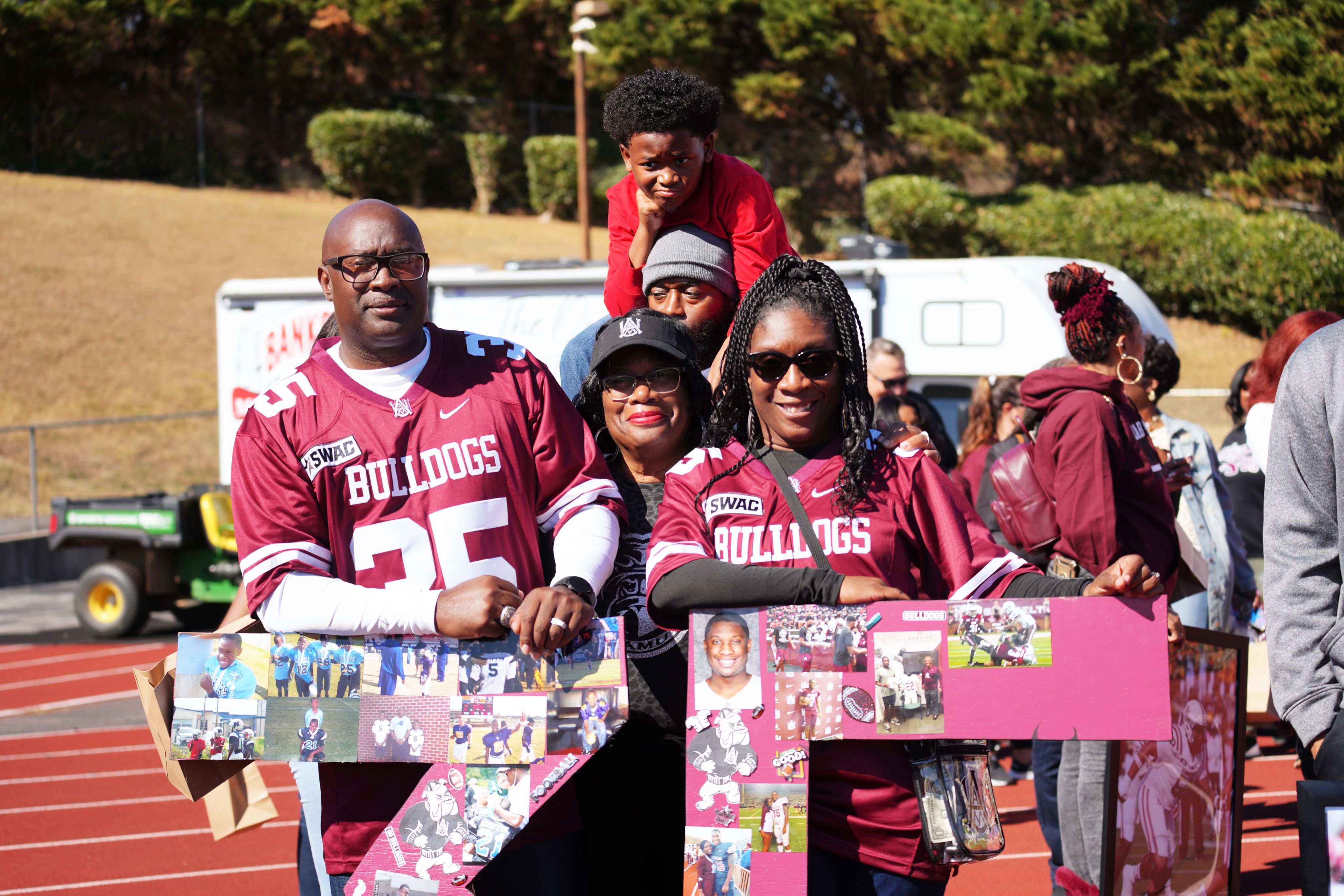 A family holding signs and wearing Bulldogs football gear outside a game.