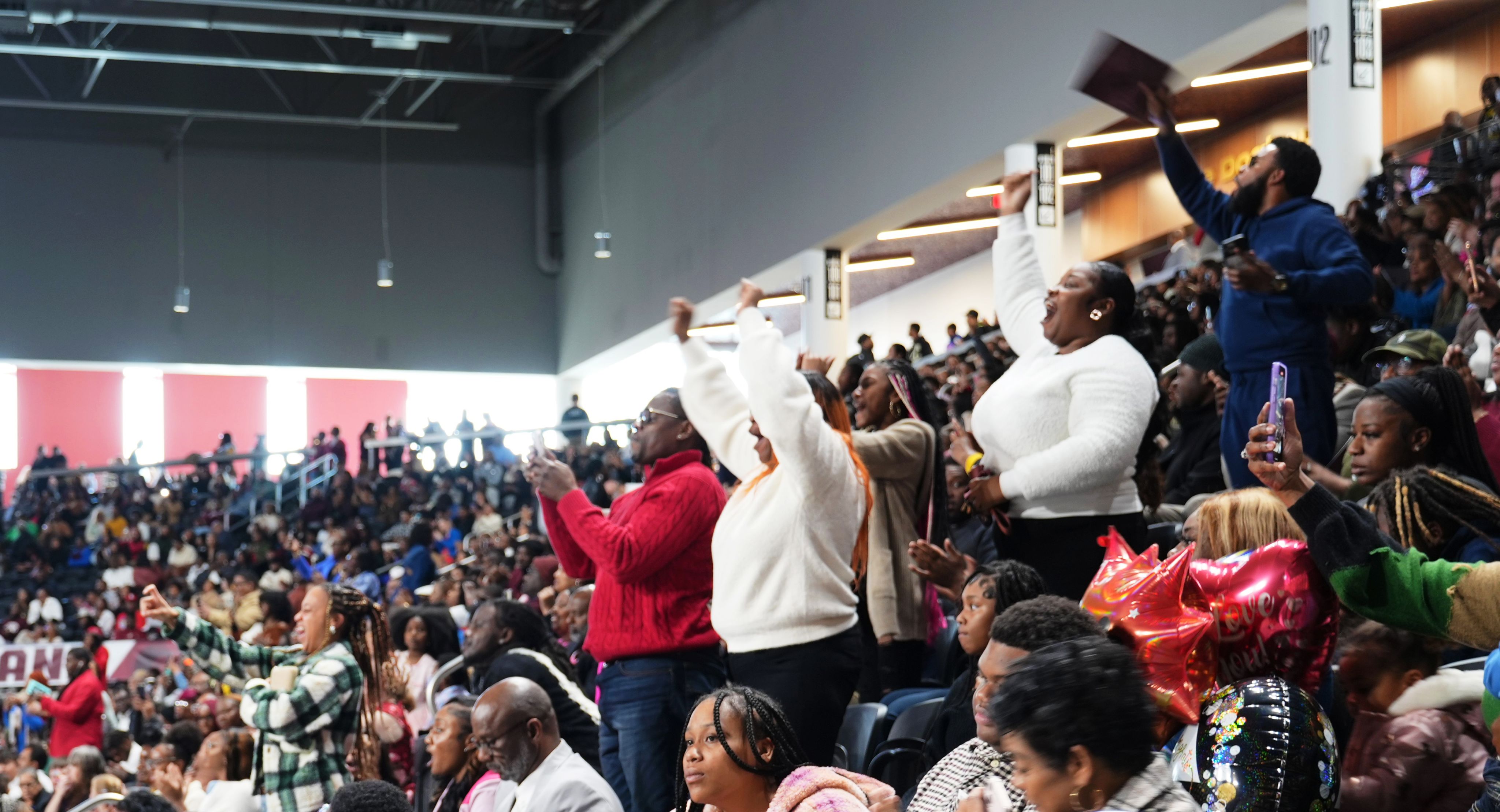 A crowd of people cheer enthusiastically at graduation.