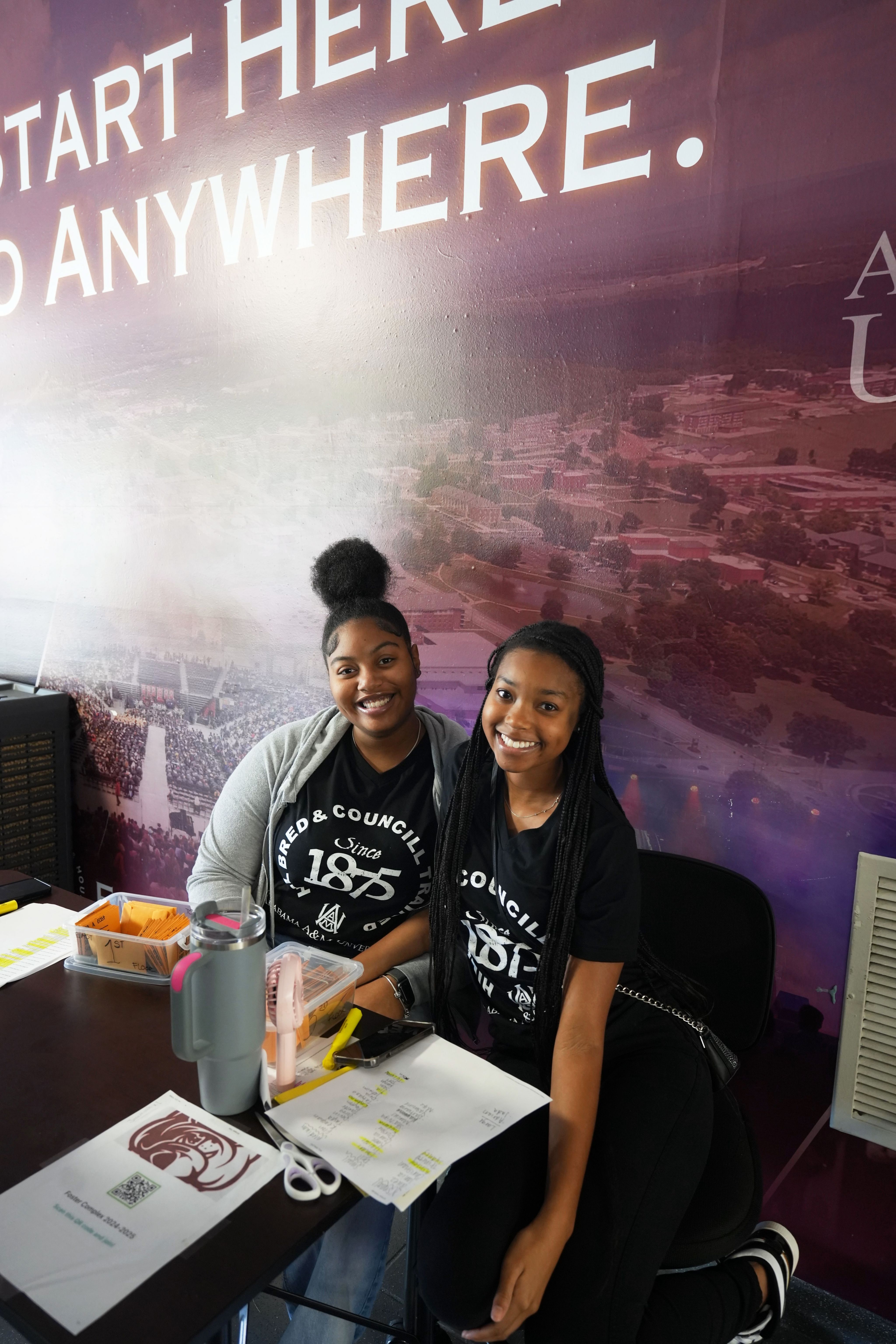 Two students sitting at a table together and smiling at the camera.