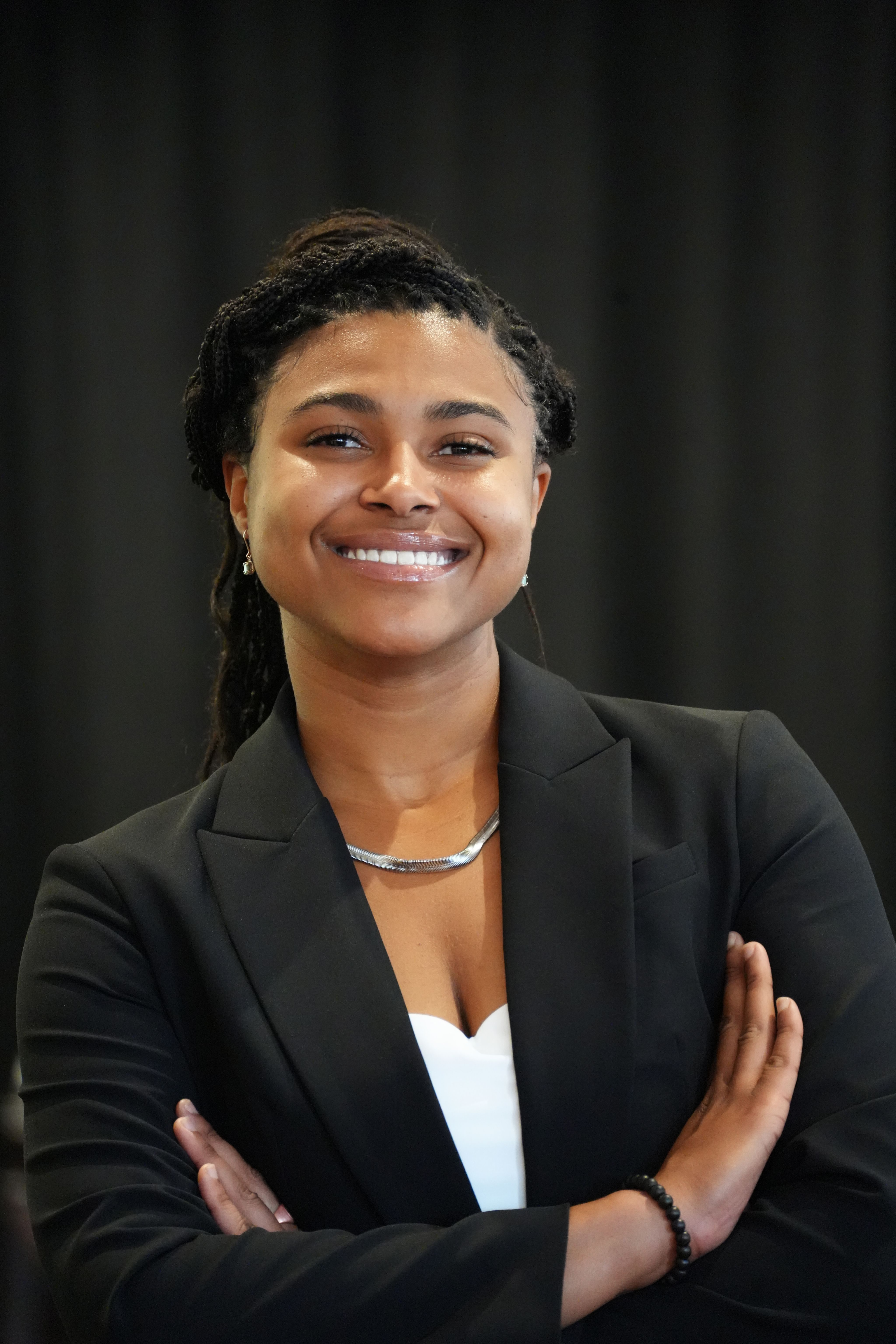 A student in business attire, smiling with arms crossed.