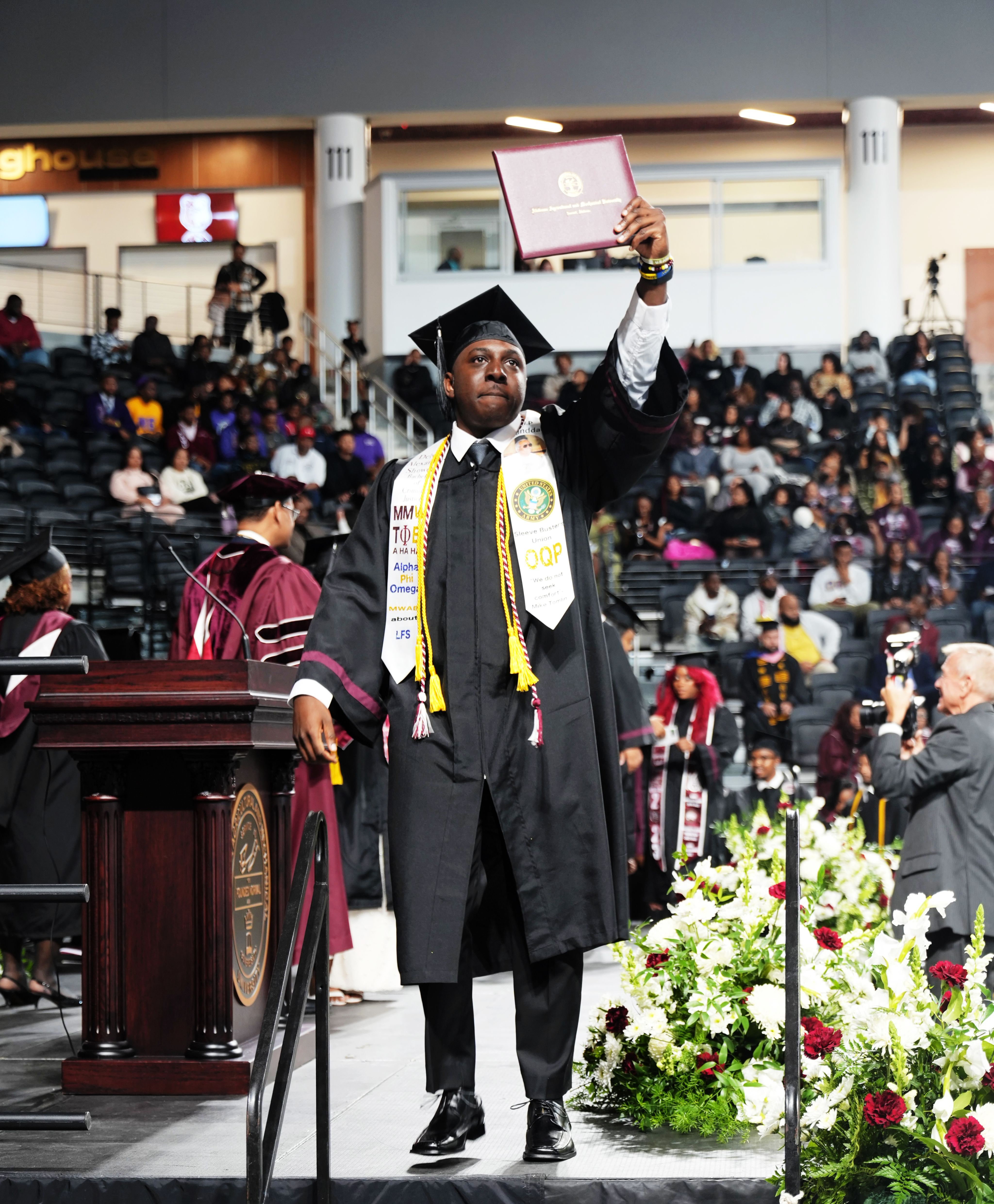 A student proudly holding up his diploma on graduation day.
