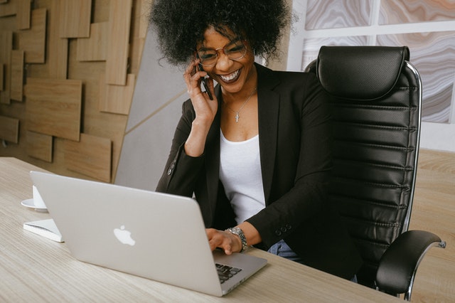 Woman sitting infront of apple laptop laughing